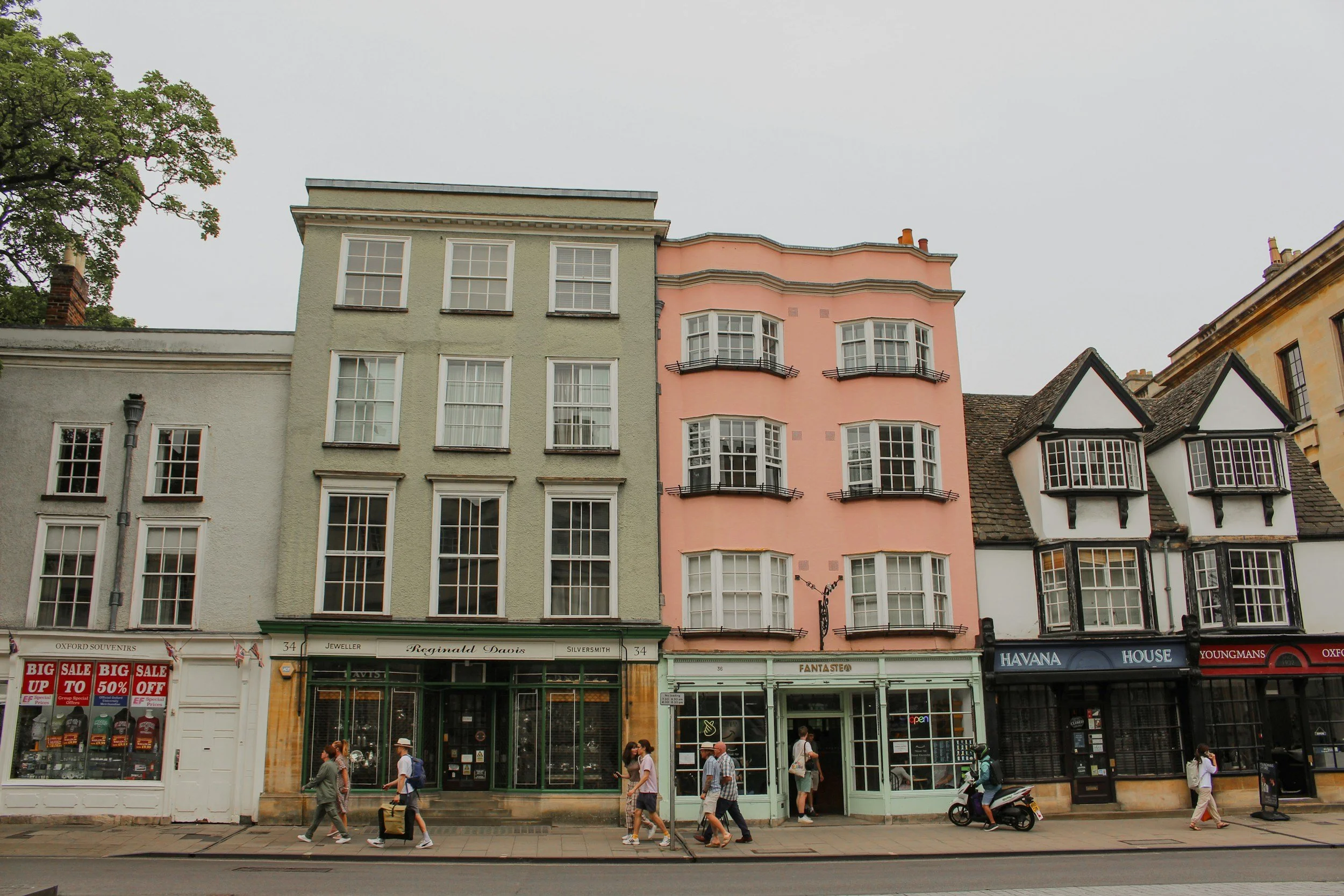 Colorful buildings along a city street with pedestrians walking and storefronts at ground level.