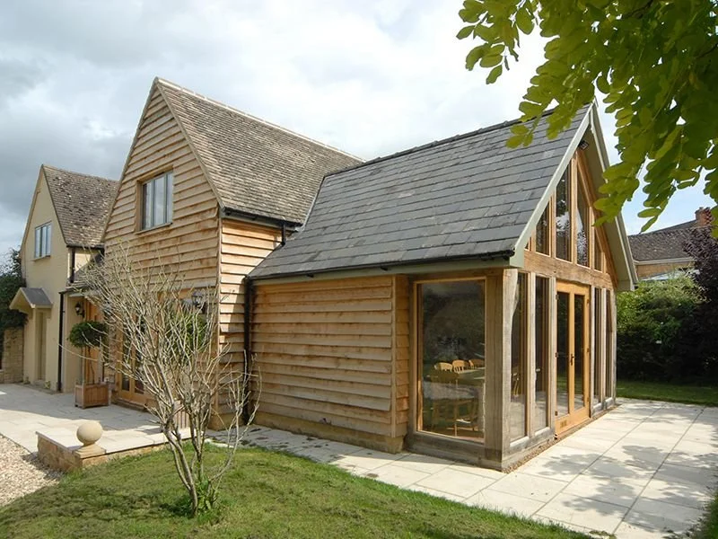A wooden house with a steep gable roof and large glass windows.