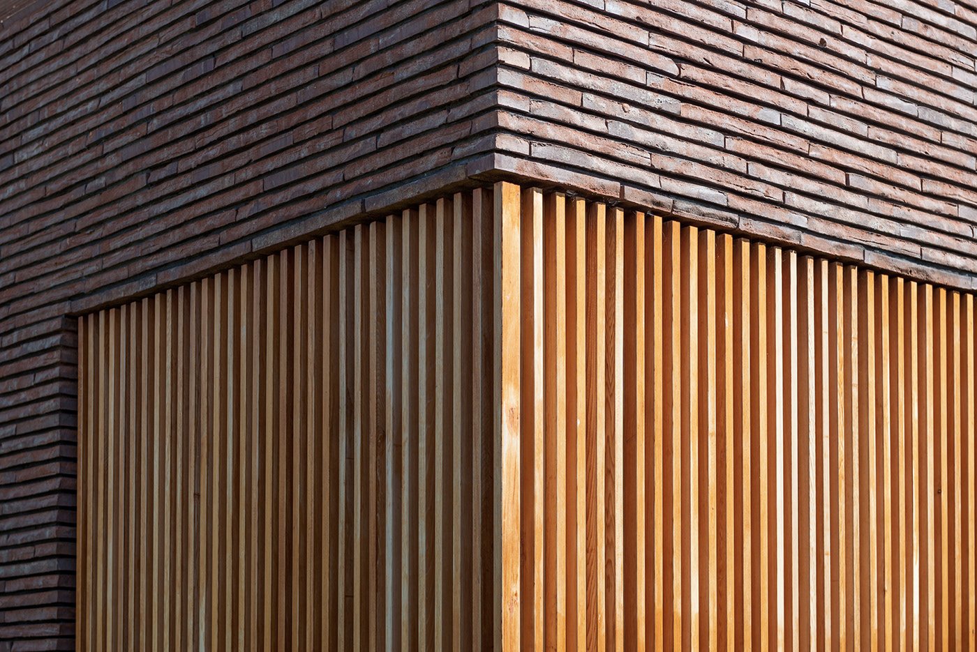 Close-up of a building corner with brick and wooden slat exterior.