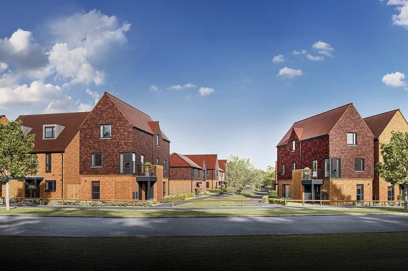 A row of modern brick houses with gabled roofs on a residential street under a blue sky with clouds.