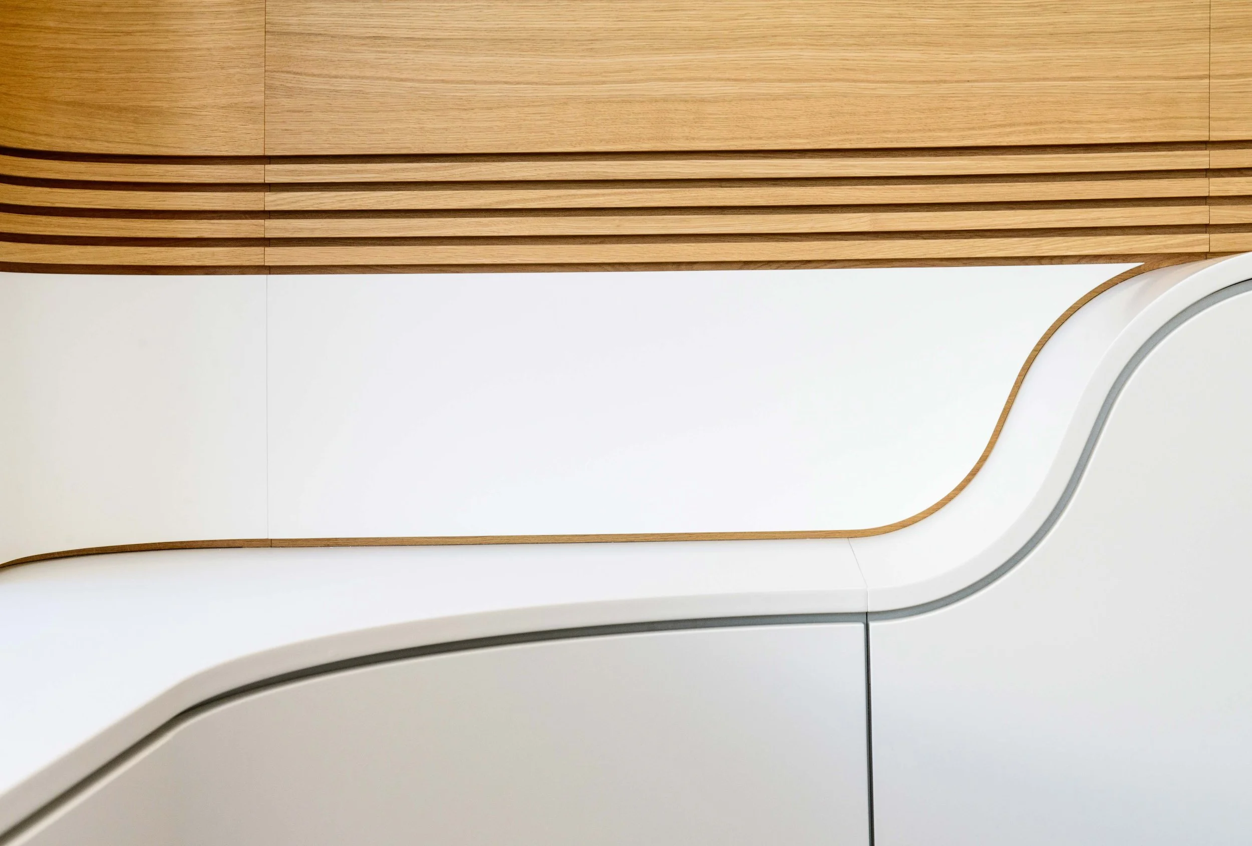 Nahaufnahme eines modernen, weißen und holzverkleideten Innenraumdesigns mit geschwungenen Linien.
