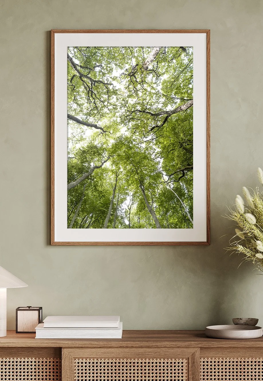 Ein Wandbild zeigt eine Blick nach oben in den Baumkronen eines Waldes, mit grünem Laub und sichtbaren Himmel. Motiv entstand im Gespensterwald, Norddeutschland