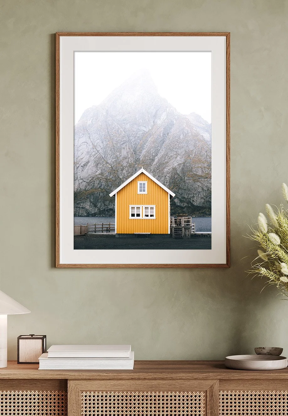 Ein gelbes Haus vor einem Berg mit schneebedecktem Gipfel. Foto in Hochformat Rahmen an der Wand