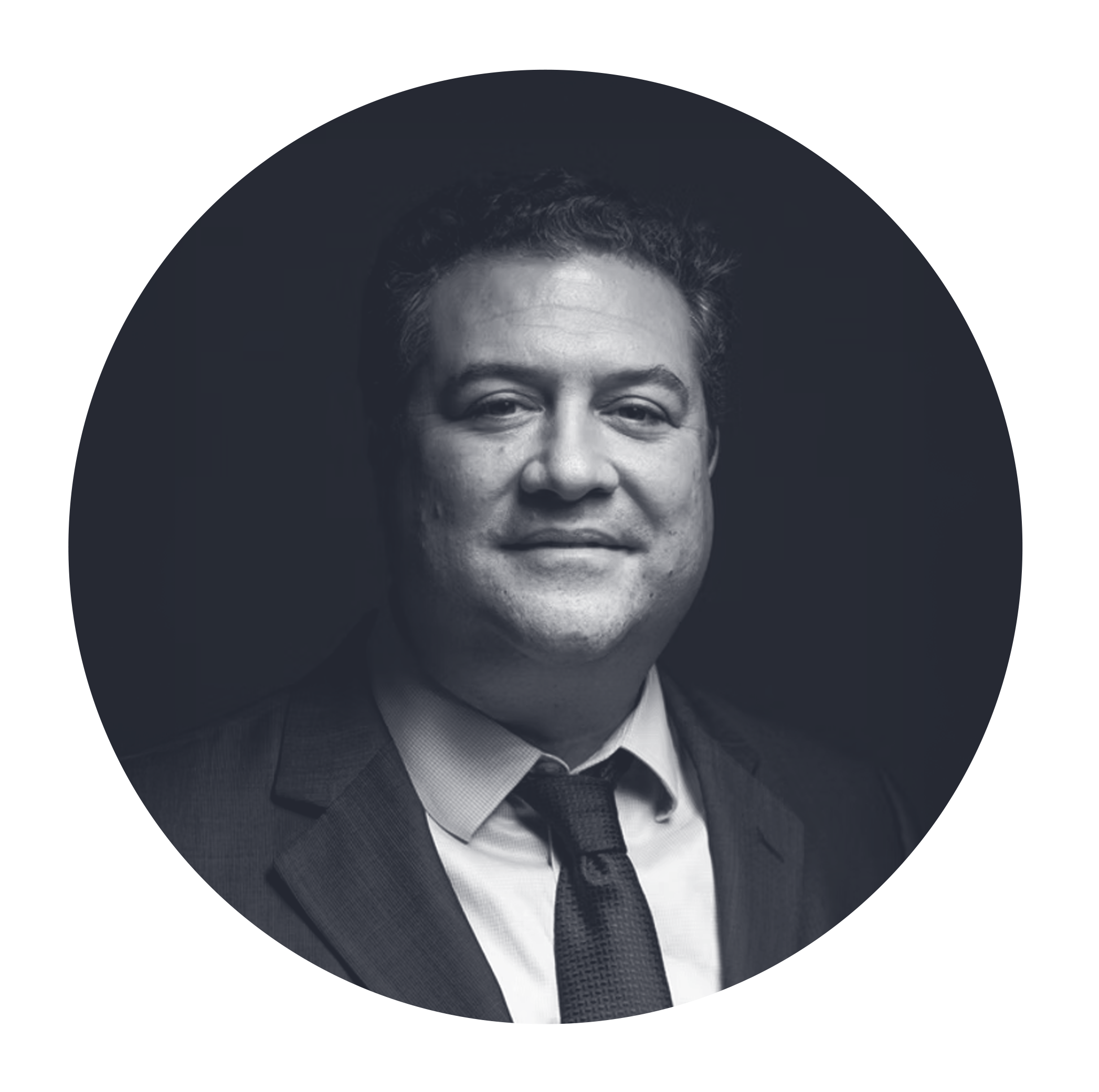 Black and white headshot of a man in a suit and tie, smiling slightly, with a dark background.