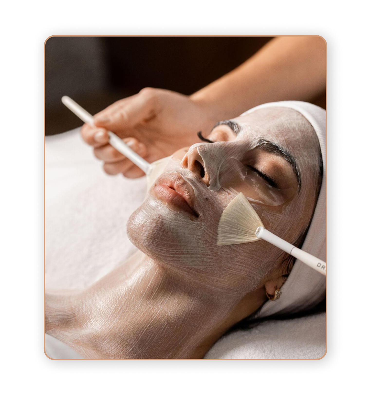 Una donna riceve un trattamento di bellezza, con una maschera facciale e strumenti applicati sul viso in un contesto di spa