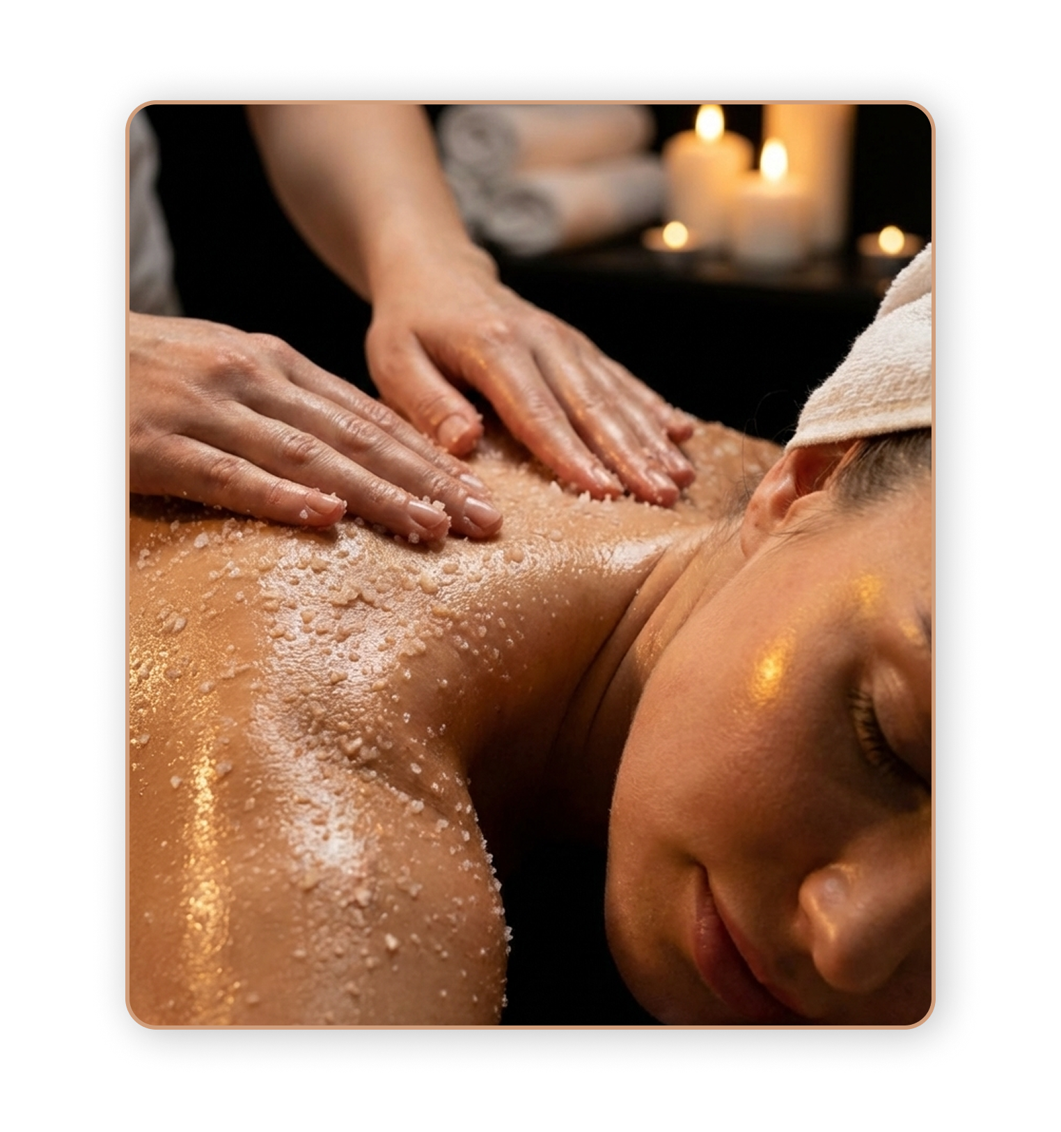 Una donna riceve un massaggio rilassante, sdraiata a pancia in giù con un asciugamano sulla testa, mentre due mani le stendono sale o scrub sulla schiena. Sullo sfondo, ci sono candele accese che creano un'atmosfera calda e rilassante.