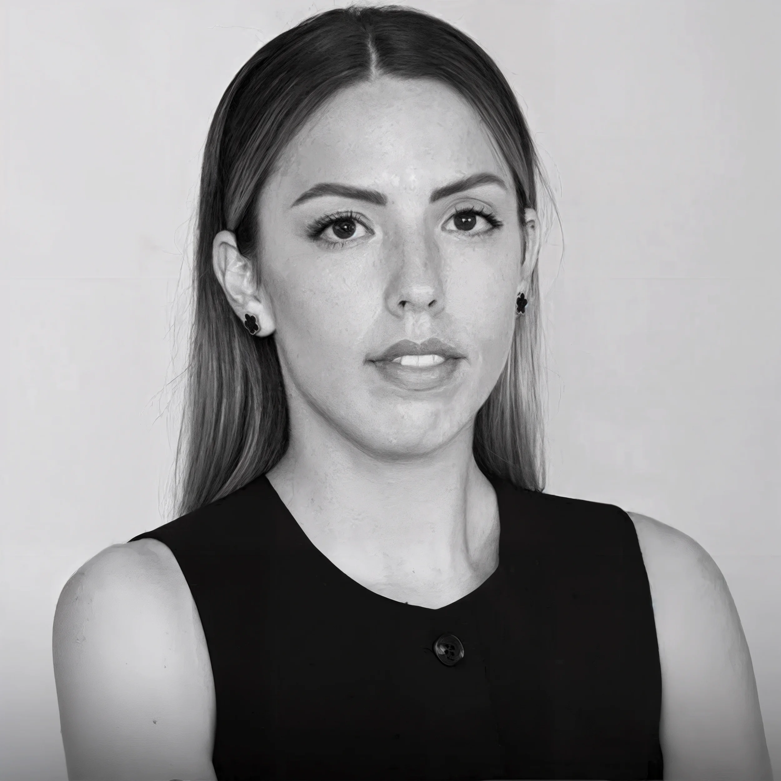 Ritratto di una donna con capelli lunghi, indossa orecchini a fiore e un vestito nero con schiena scoperta, sfondo semplice