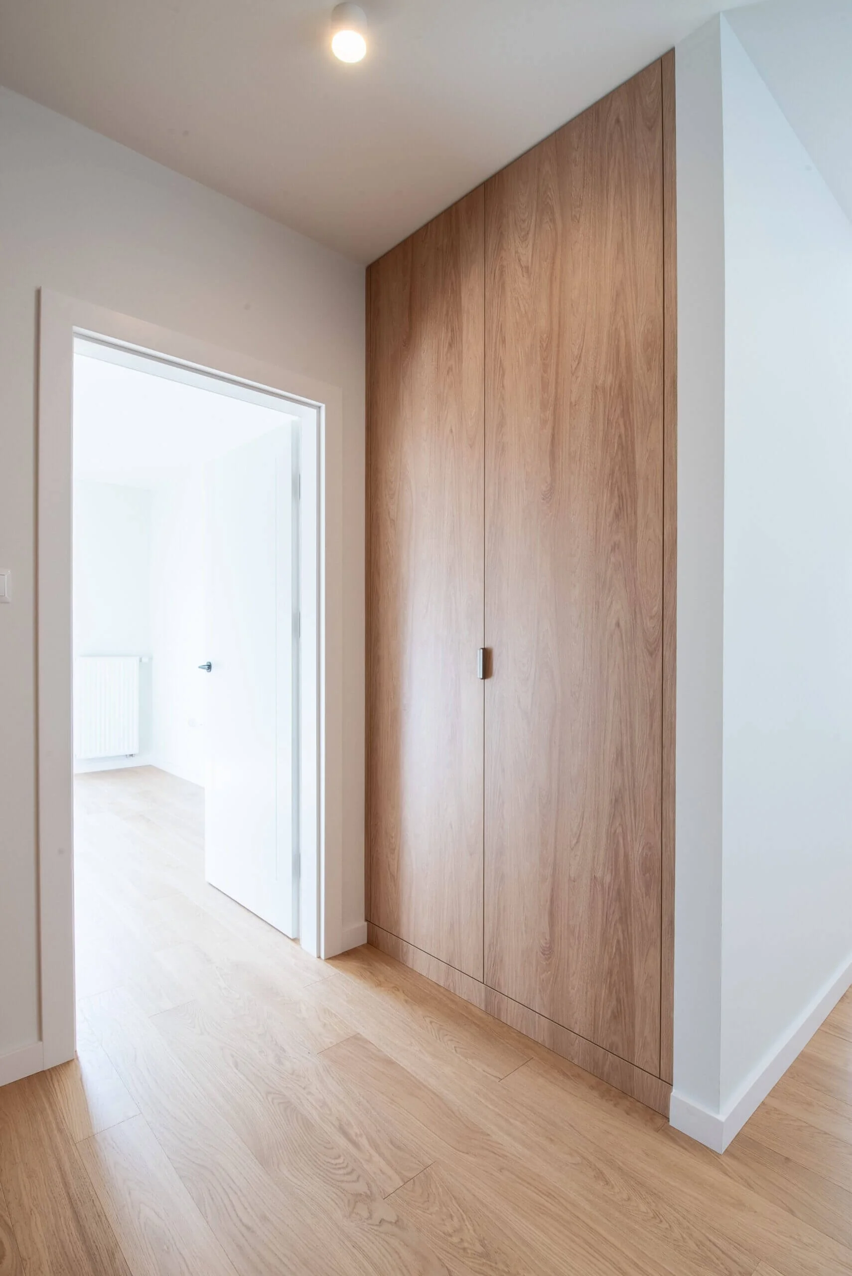 Menuiserie sur mesure : pose de porte intérieure en bois dans un couloir moderne. Alfatech réalise vos aménagements intérieurs avec des finitions soignées et un souci du détail.