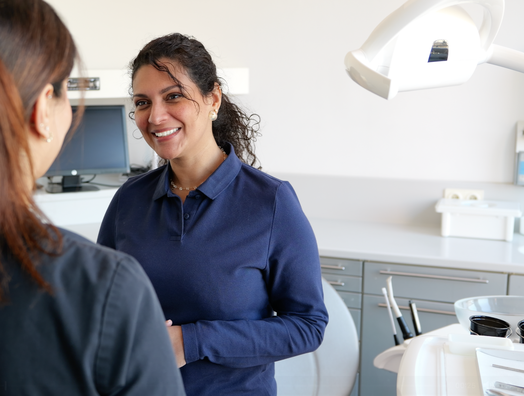 Two women in a dentist office smiling and having a conversation.