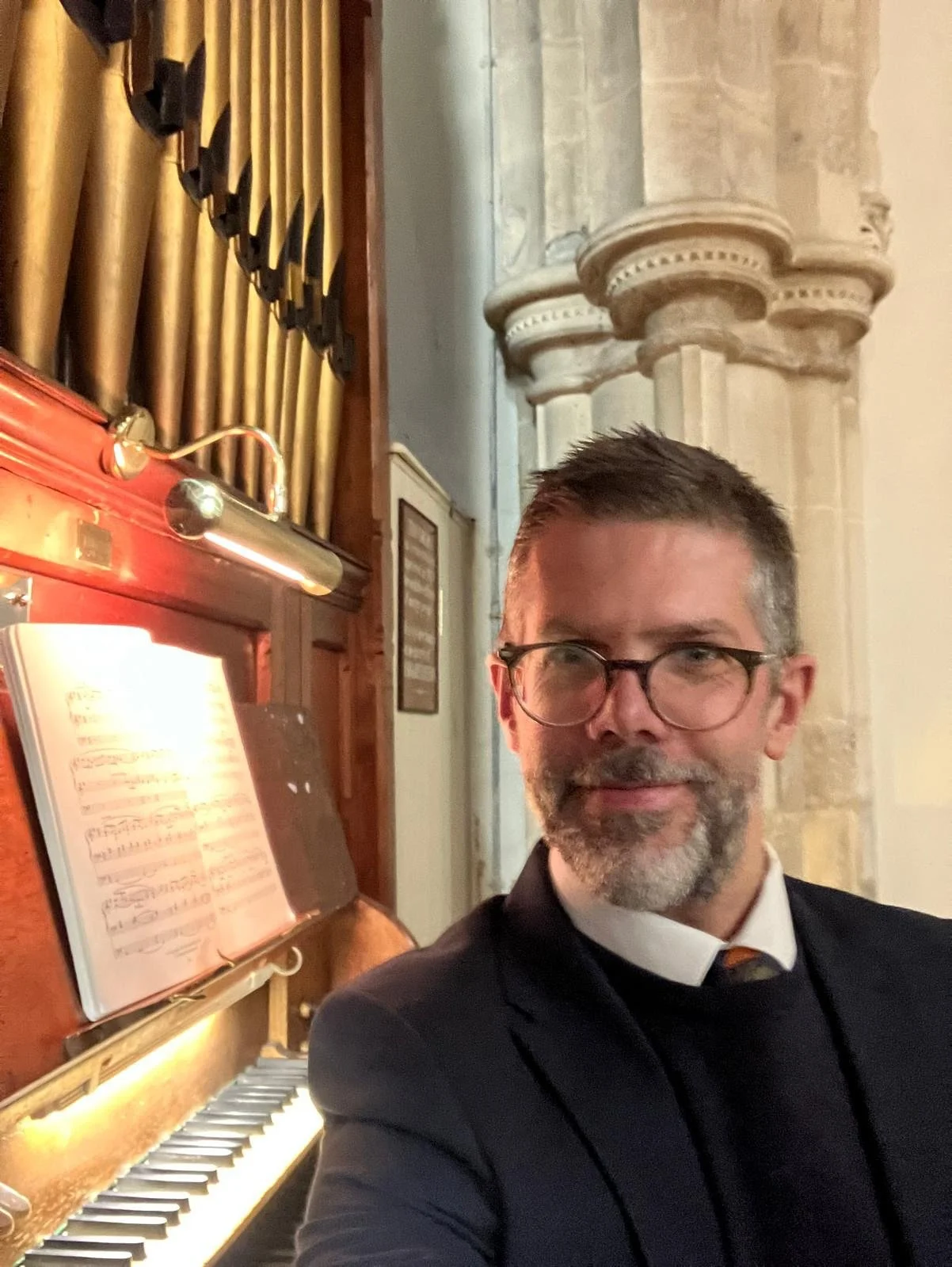 Organist Ben Humphries sat at the organ console ready to play organ music for a special baptism service at the beautiful All Hallows Church in South Cerney, Gloucestershire