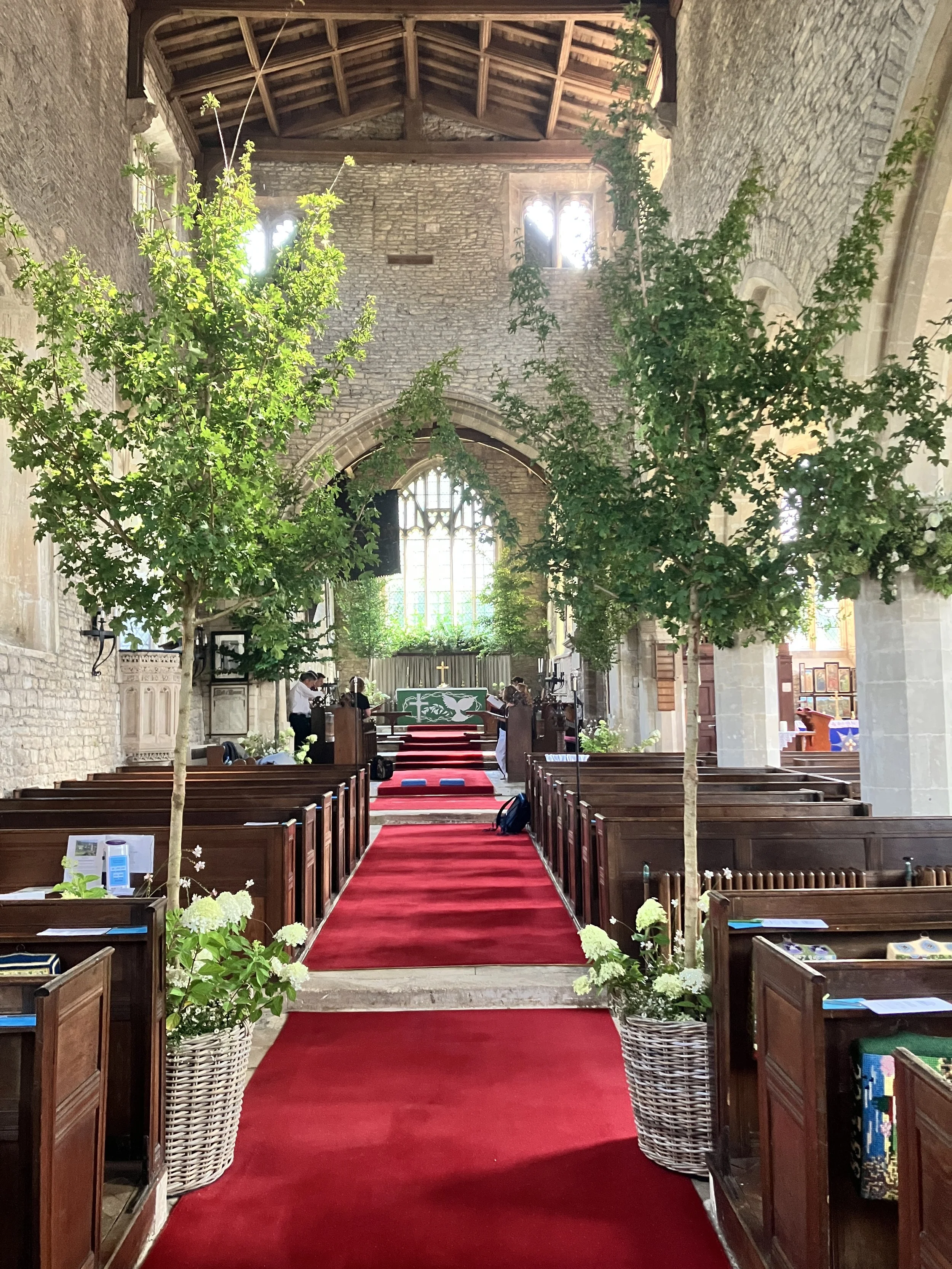 Impressive floral display at St Mary the Virgin Church in Hawkesbury Upton, Gloucestershire with celebratory music played by the organist Ben Humphries before this wedding ceremony. 