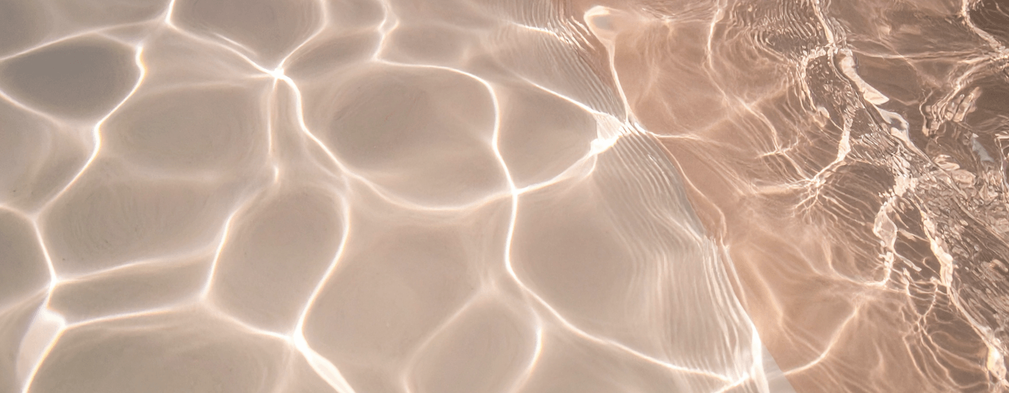 Close-up of clear water surface with sunlight creating a pattern of ripples and reflections.