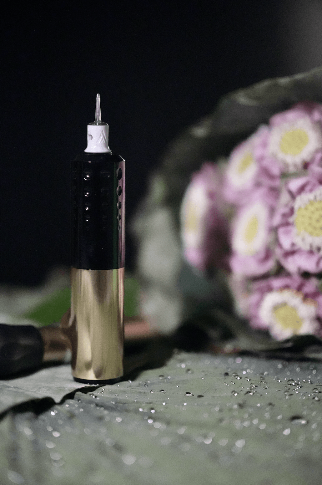 Tattoo machine with Vertix needle cartridge on lotus leaf and flowers.