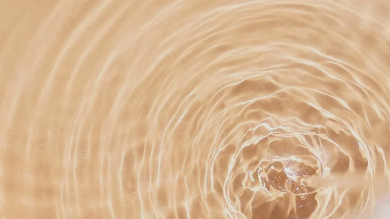 Close-up of rippling water with a small splash creating concentric circles.