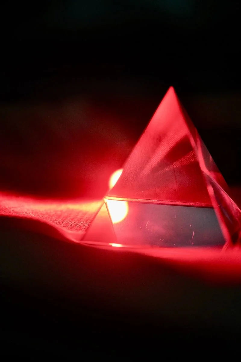 Healing light shining on triangular prism as a representation of red-light therapy science used in cosmetic tattooing.