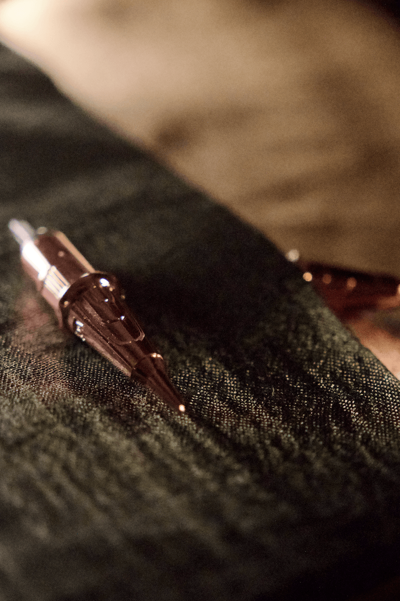 The ultra-fine tattoo needle on a soft silk texture, symbolising soft lip technique for sophisticated gradient and dimension for lip blush.