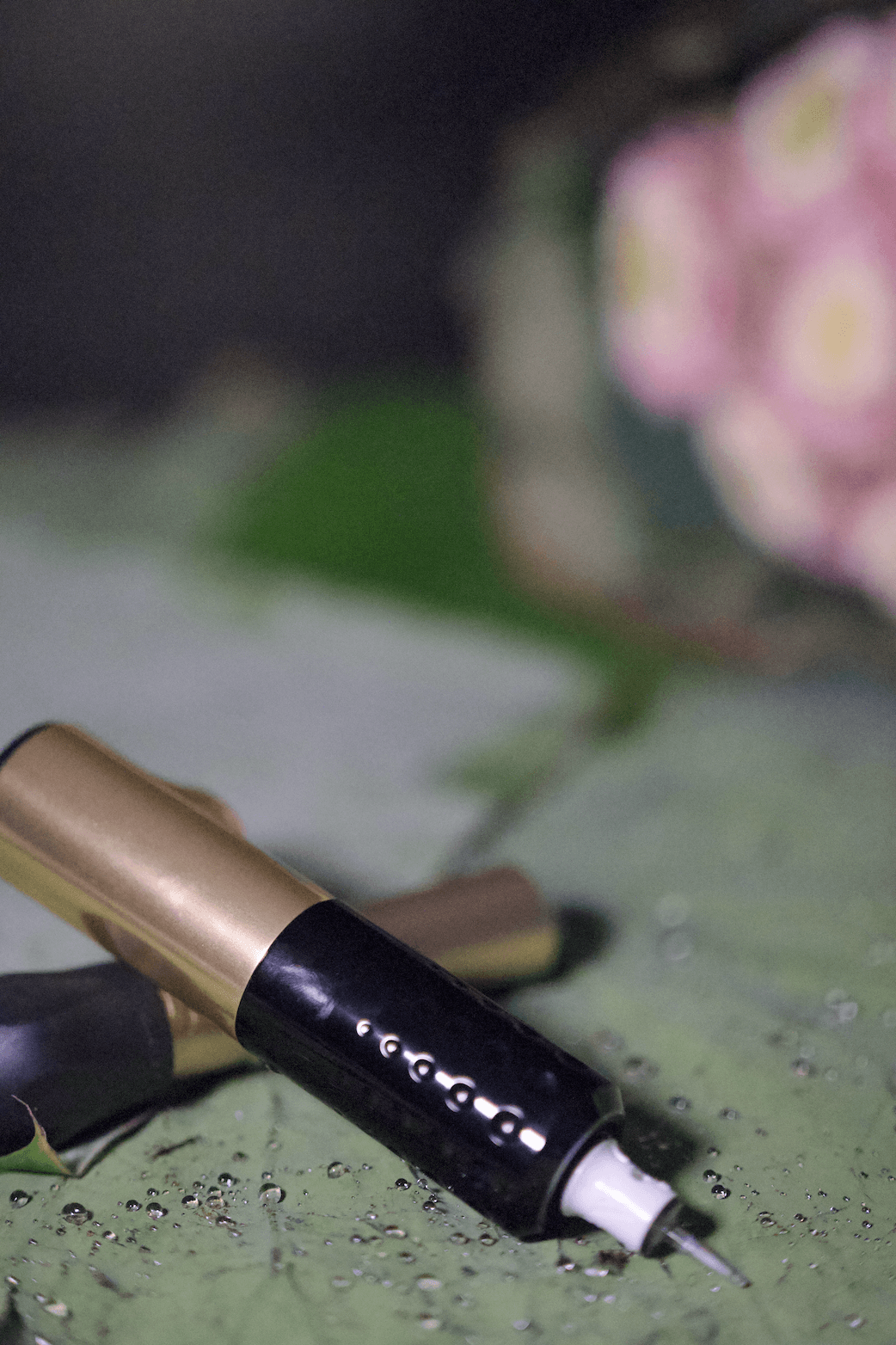 SMP tattoo machines on lotus leaf near a bunch of pink lotus flower symbolising the technique in calming, peaceful salon