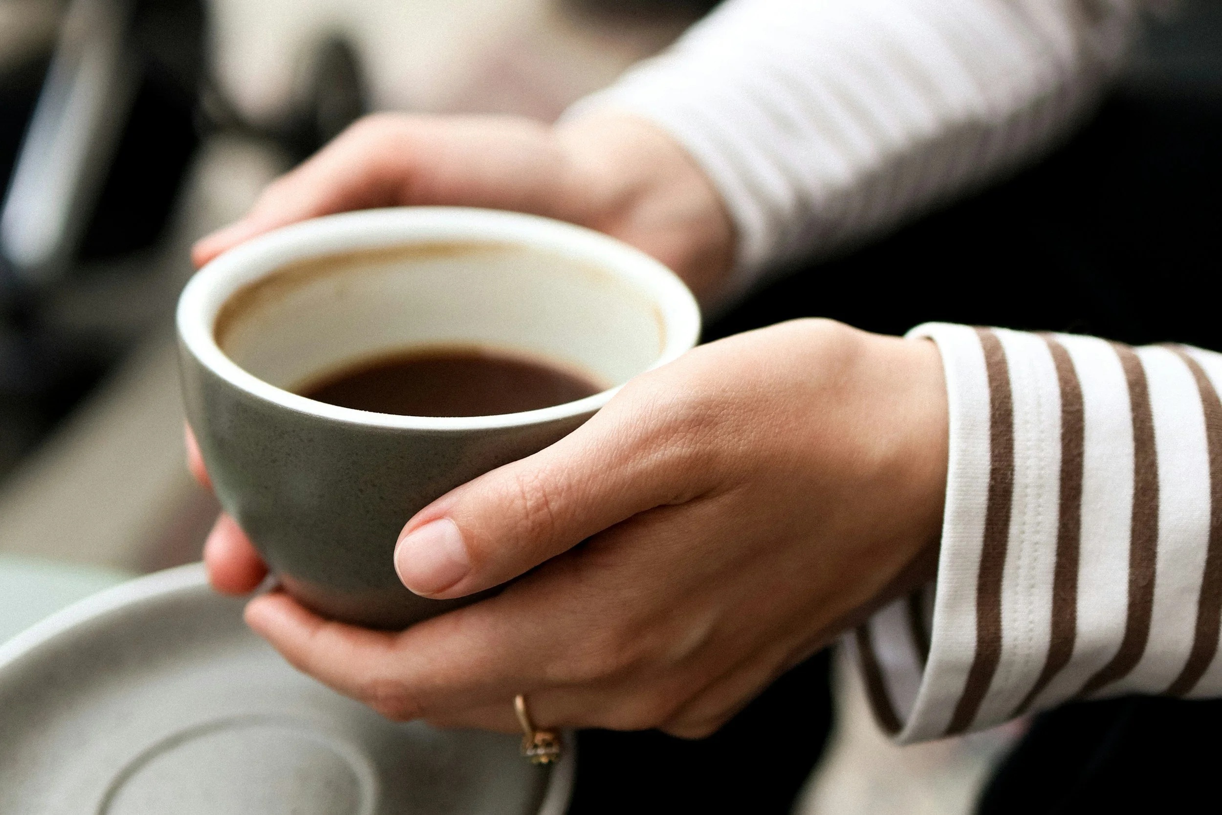Person holding a cup of coffee with both hands.
