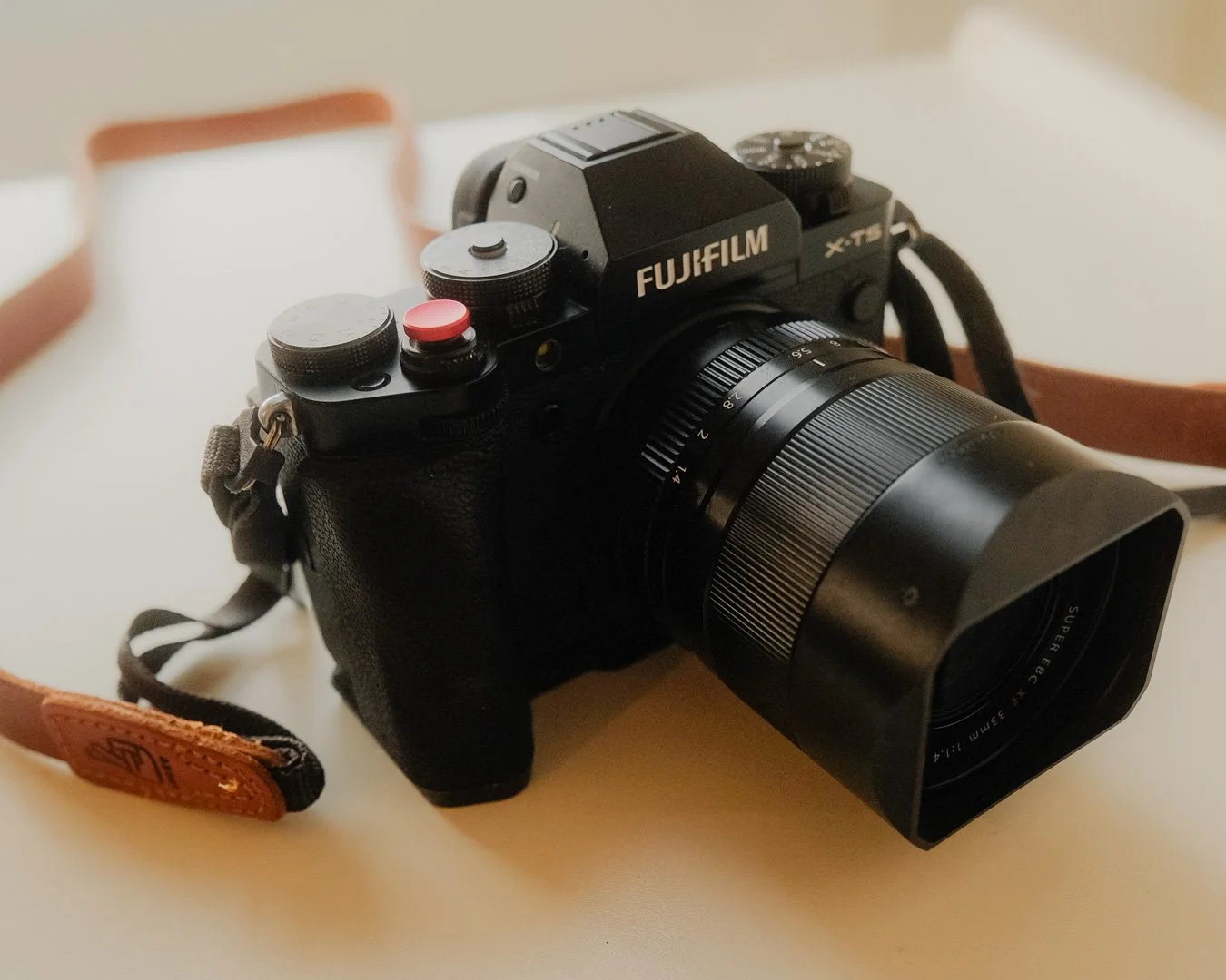 High quality image of a Fujifilm X-T5 body with a 33mm F1.4 lens and squarehood.