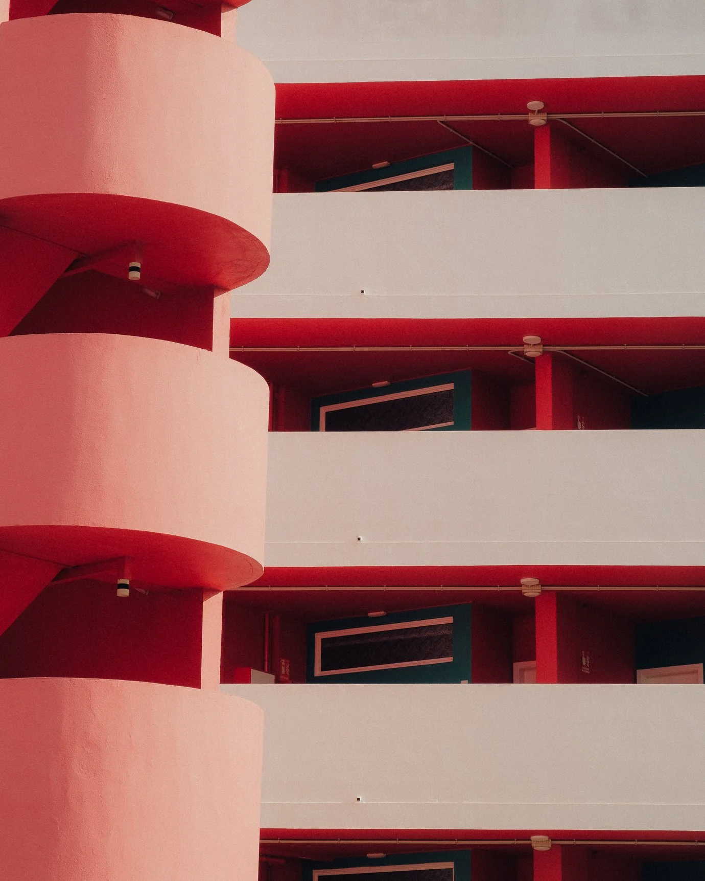 Geometric architectural detail of a pink and red building with striking shadows and modernist lines.
