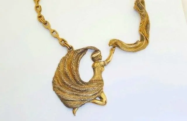 Gold necklace with a pendant shaped like a hula dancer wrapping a wave