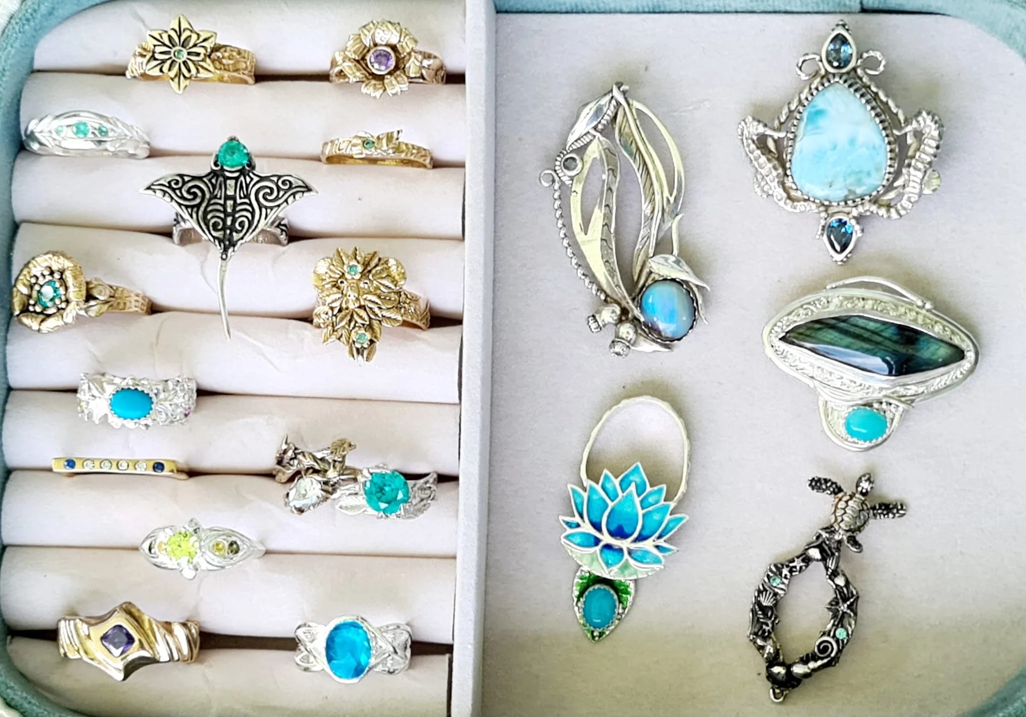 Collection of turquoise and silver jewelry including rings and brooches arranged in a jewelry box.