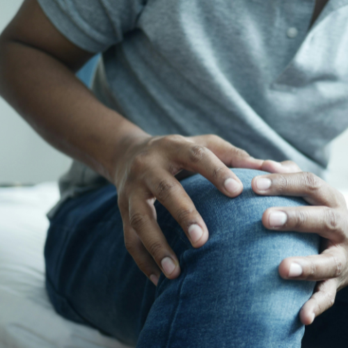 Person holding their knee, possibly experiencing pain.