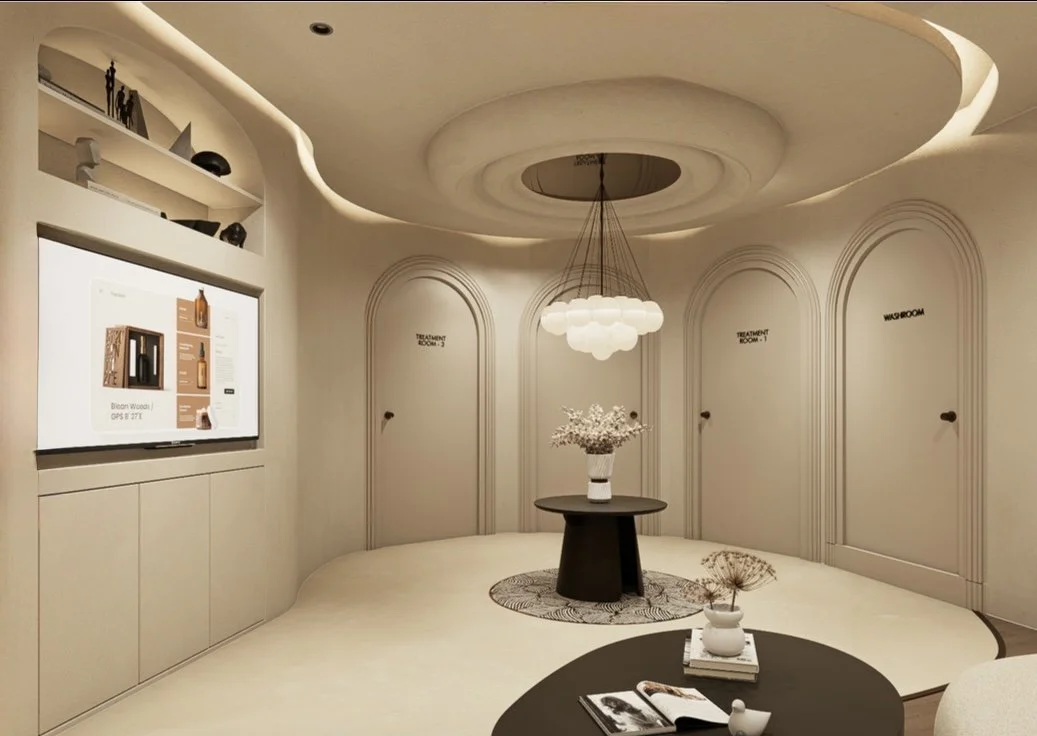 Elegant, modern interior room with neutral tones, featuring a round ceiling with a hanging chandelier, a dark round table with a white vase and flowers, and curved doorways labeled 'Treatment Room 3,' 'Treatment Room 1,' and 'Washroom.'