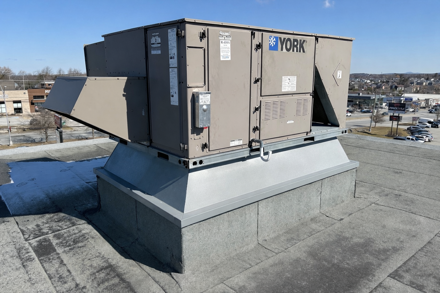 Un climatiseur de toit de marque YORK installé sur une toiture en ville, avec un ciel bleu en arrière-plan.