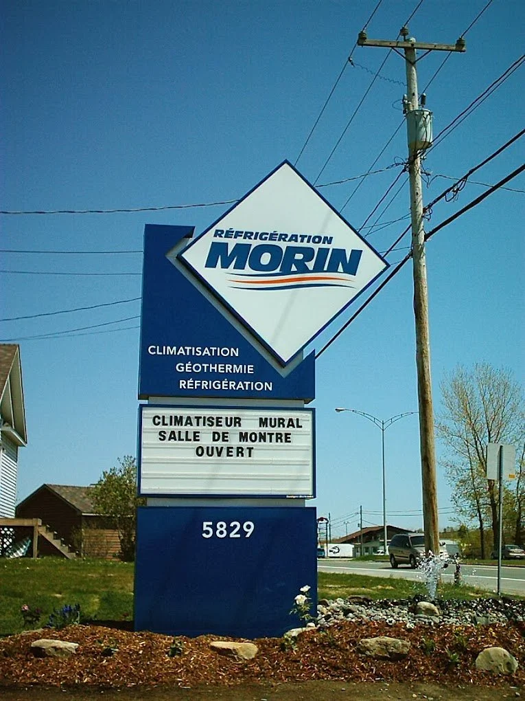 Panneau publicitaire pour une entreprise de réfrigération et climatisation, avec l'adresse 5829, en plein jour avec un ciel bleu clair.