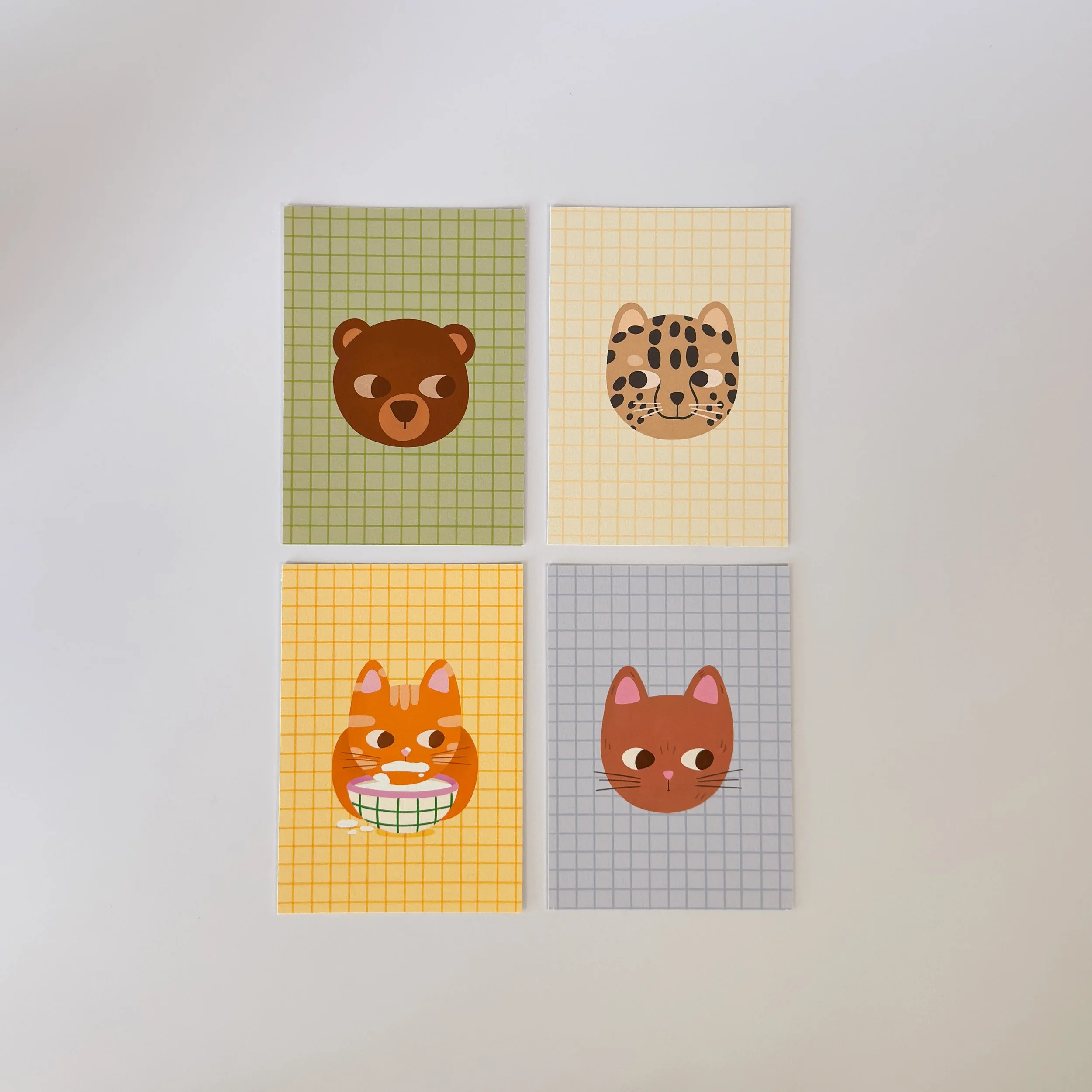 Quatre cartes postales avec des illustrations d'animaux : un ours, un guépard, un chat, et un autre chat qui boit son lait.