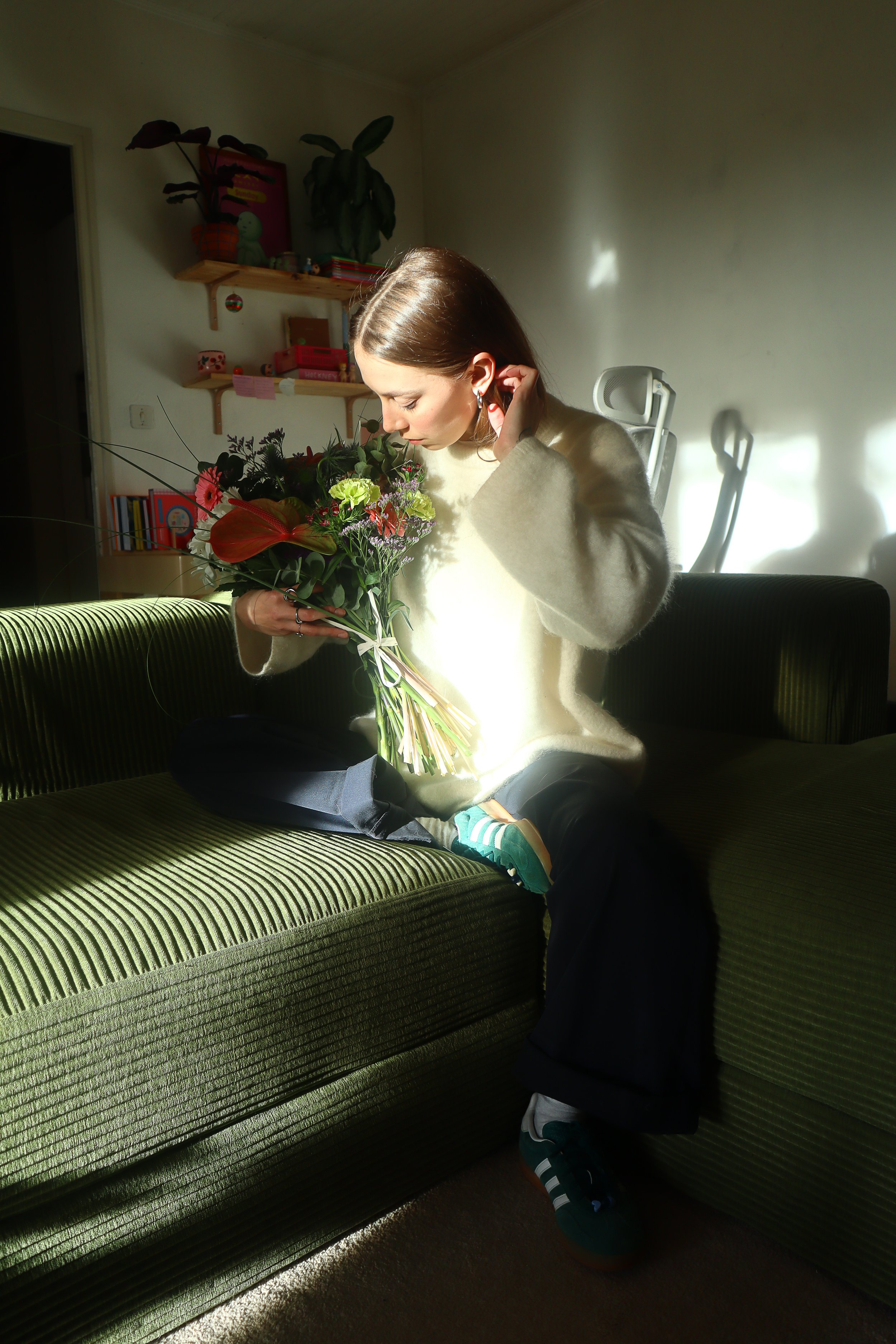 Photo de moi (Charlène) qui tient un jolie bouquet de fleurs dans mon canapé.