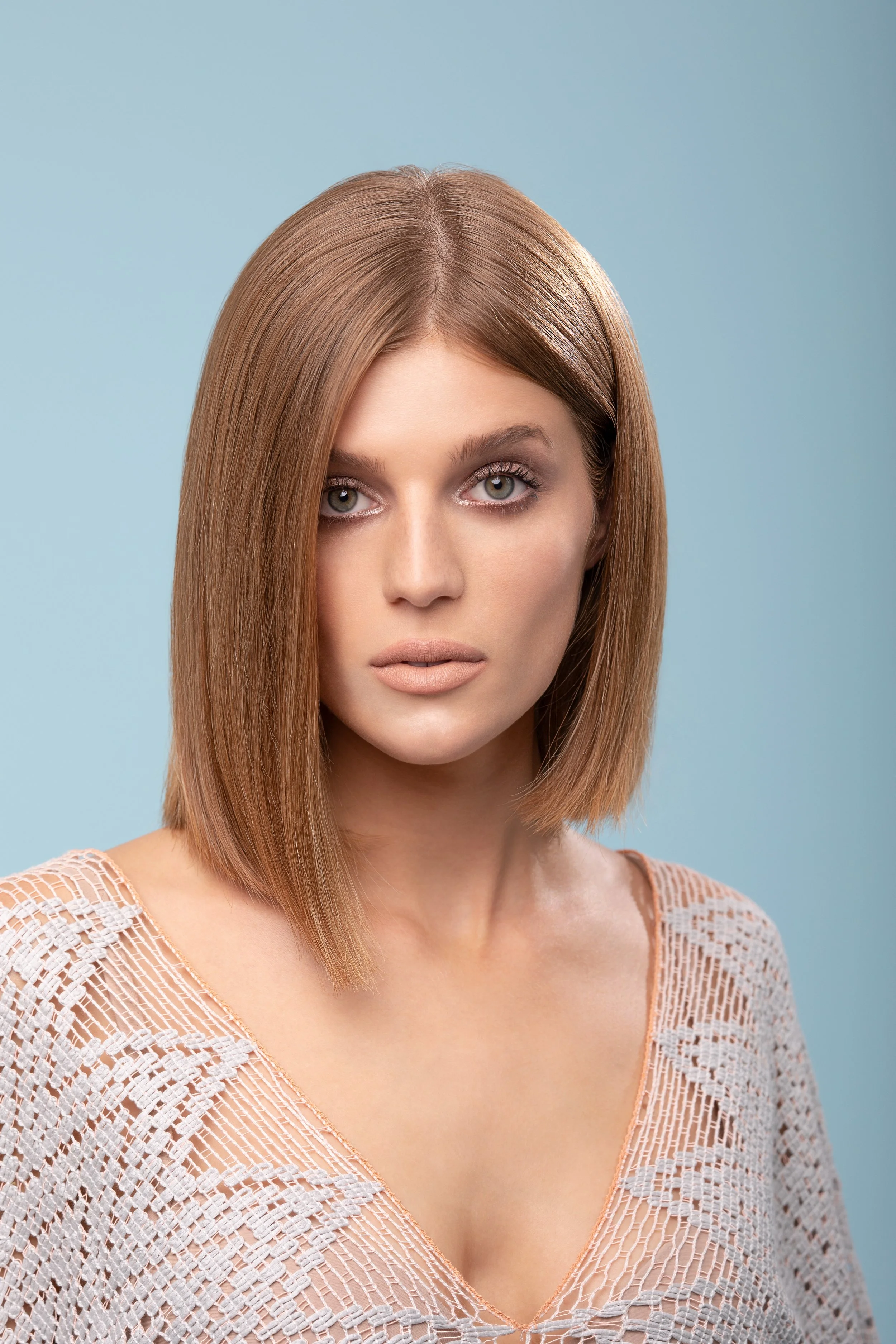 ritratto di una donna con capelli castano chiaro, sguardo diretto, sfondo azzurro