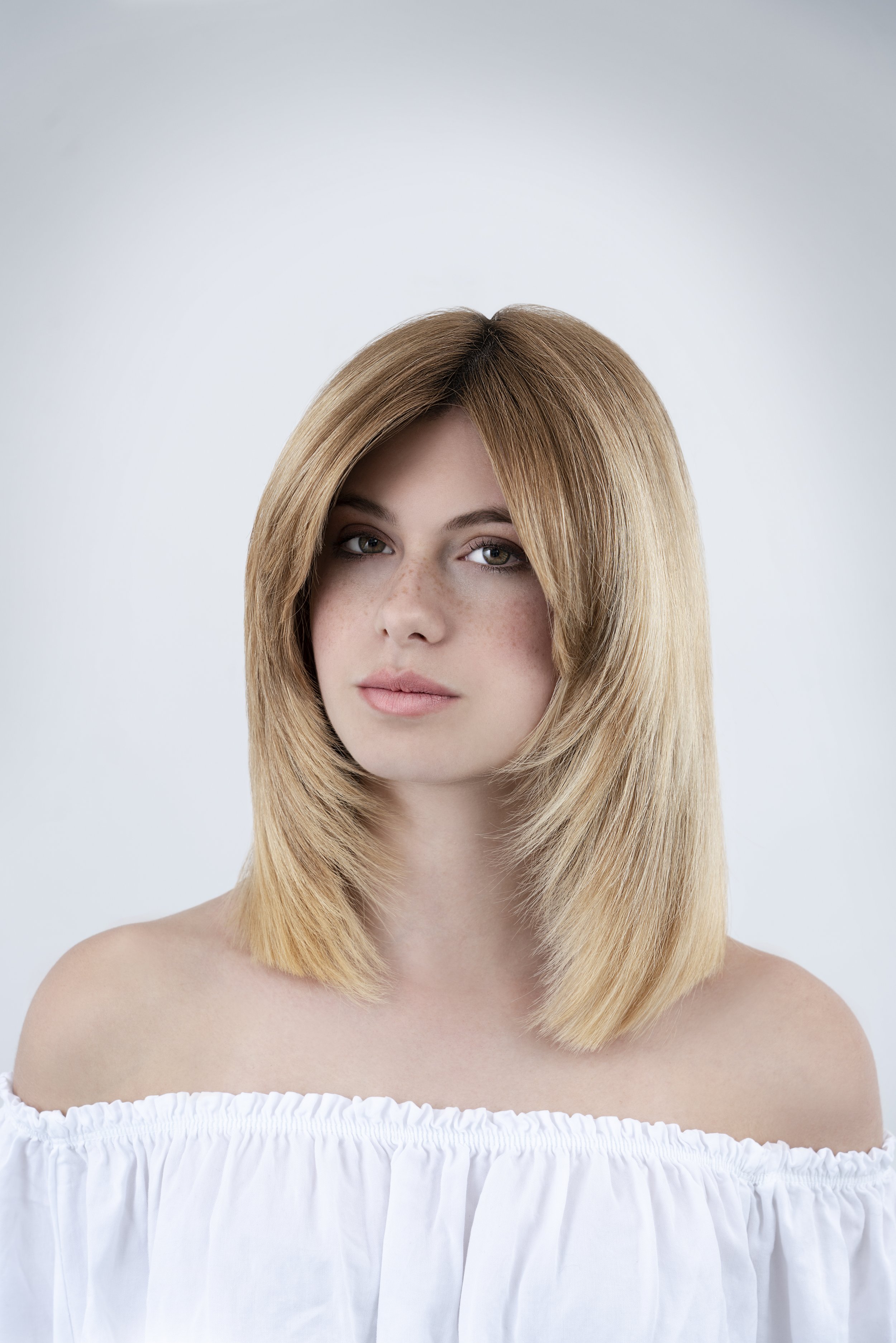 Ragazza con capelli biondi, corti e lisci, che indossa una maglietta bianca con spalle scoperte.