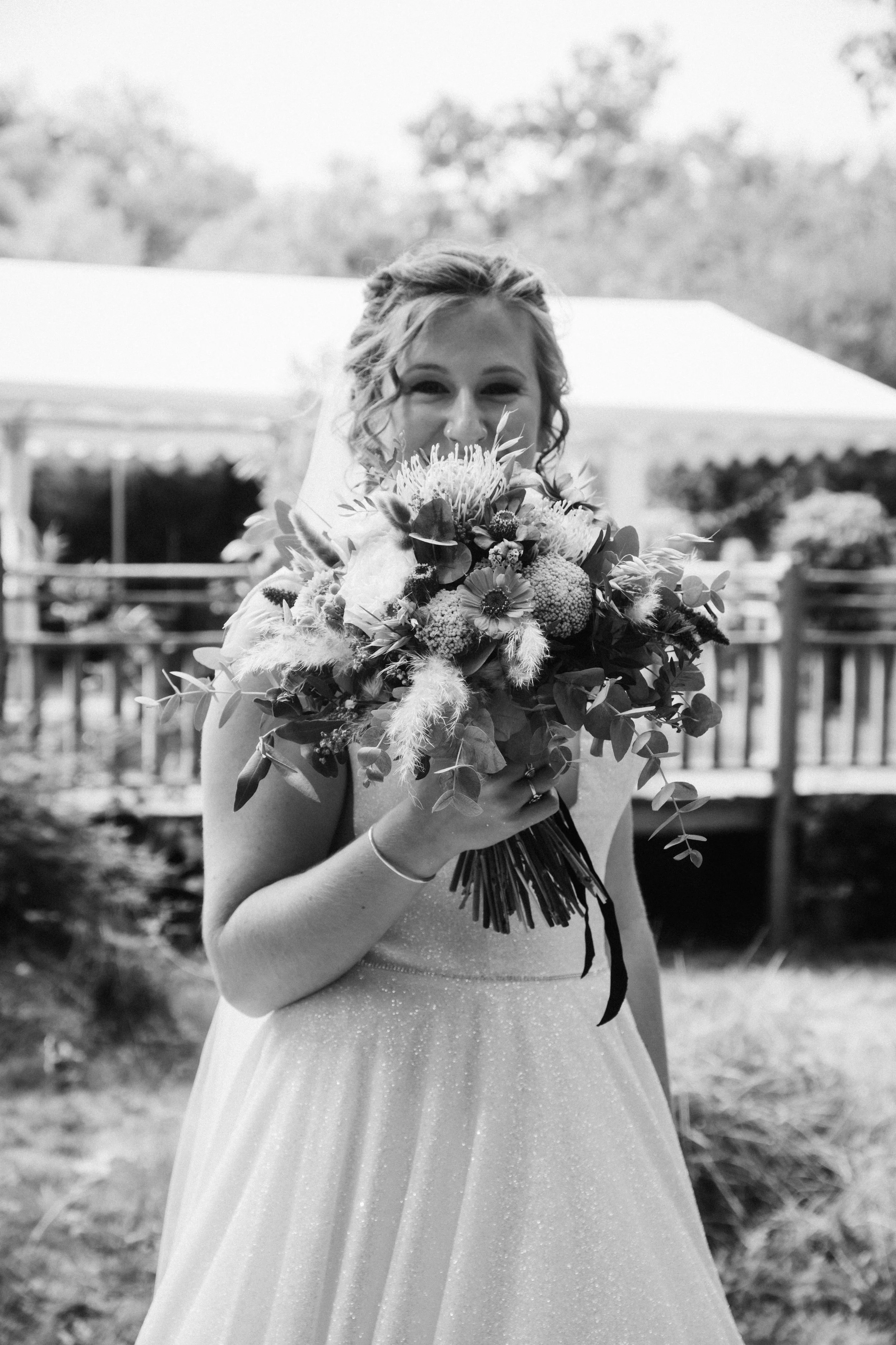 Une femme en robe de mariée tenant un bouquet de fleurs lors d'un mariage en plein air.