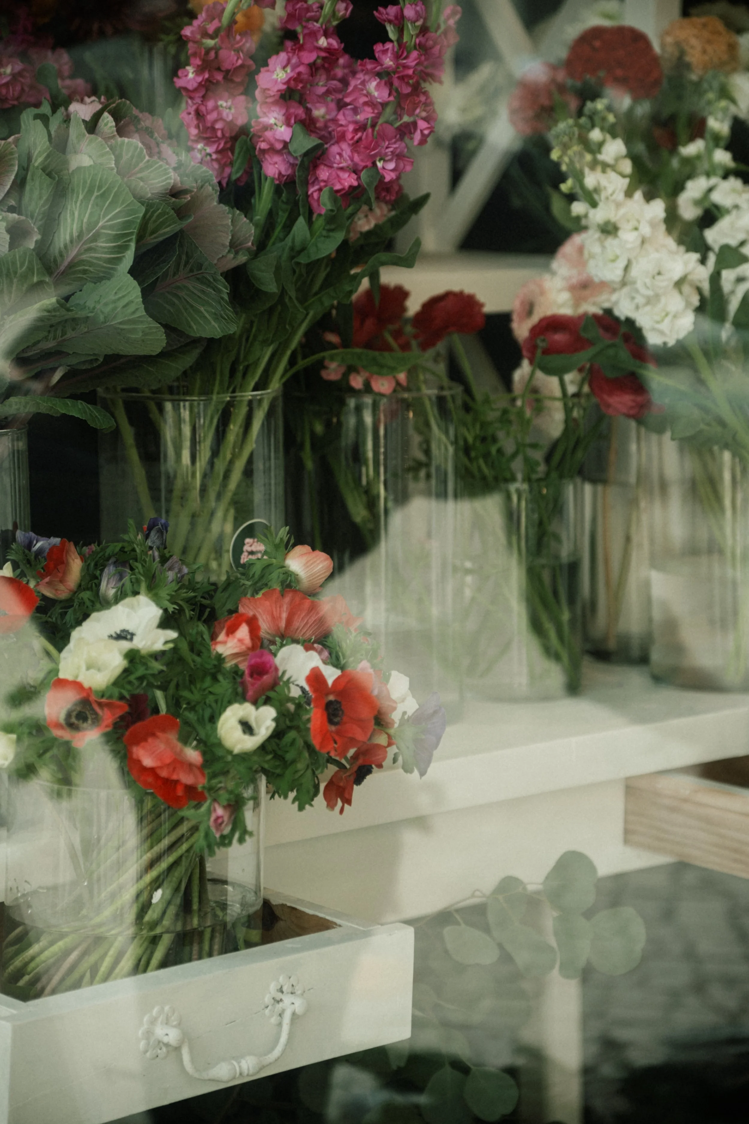 Fleurs variées dans des vases en verre sur une étagère dans une boutique de fleurs.