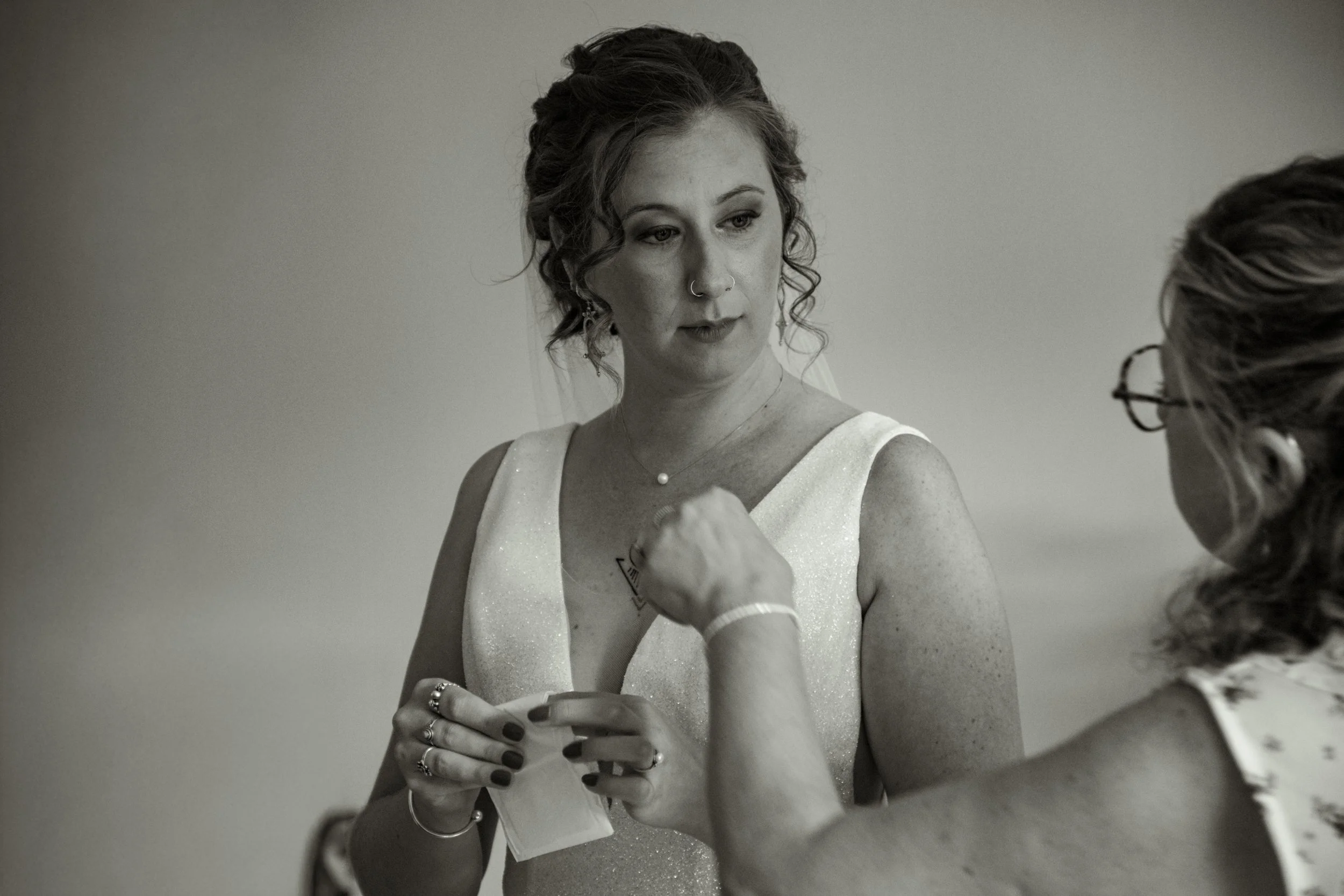 Une femme en robe de mariée recevant une larme de maquilleuse lors de son mariage.