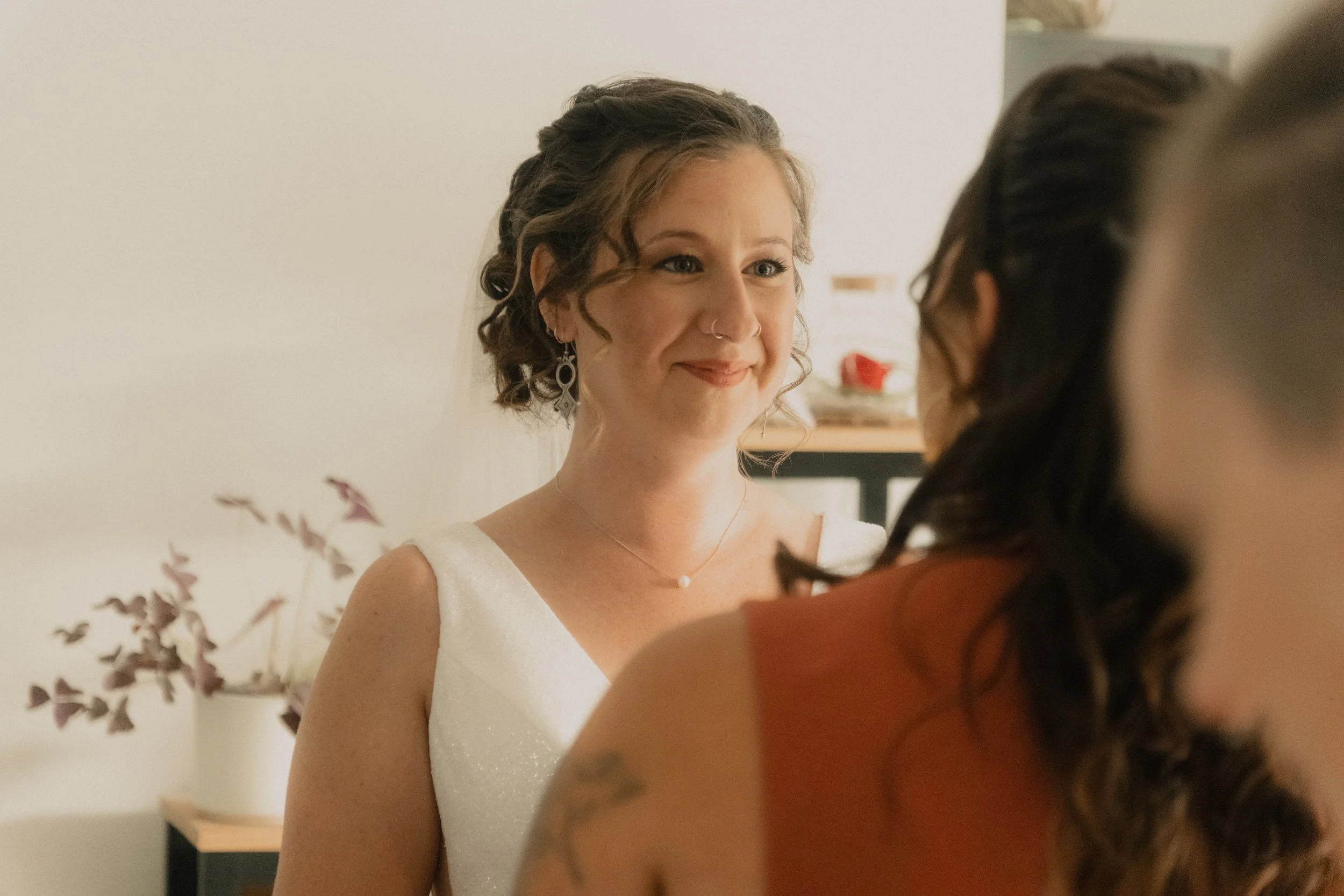 Une femme souriante portant une robe blanche regarde une autre personne dont le visage n'est pas visible.