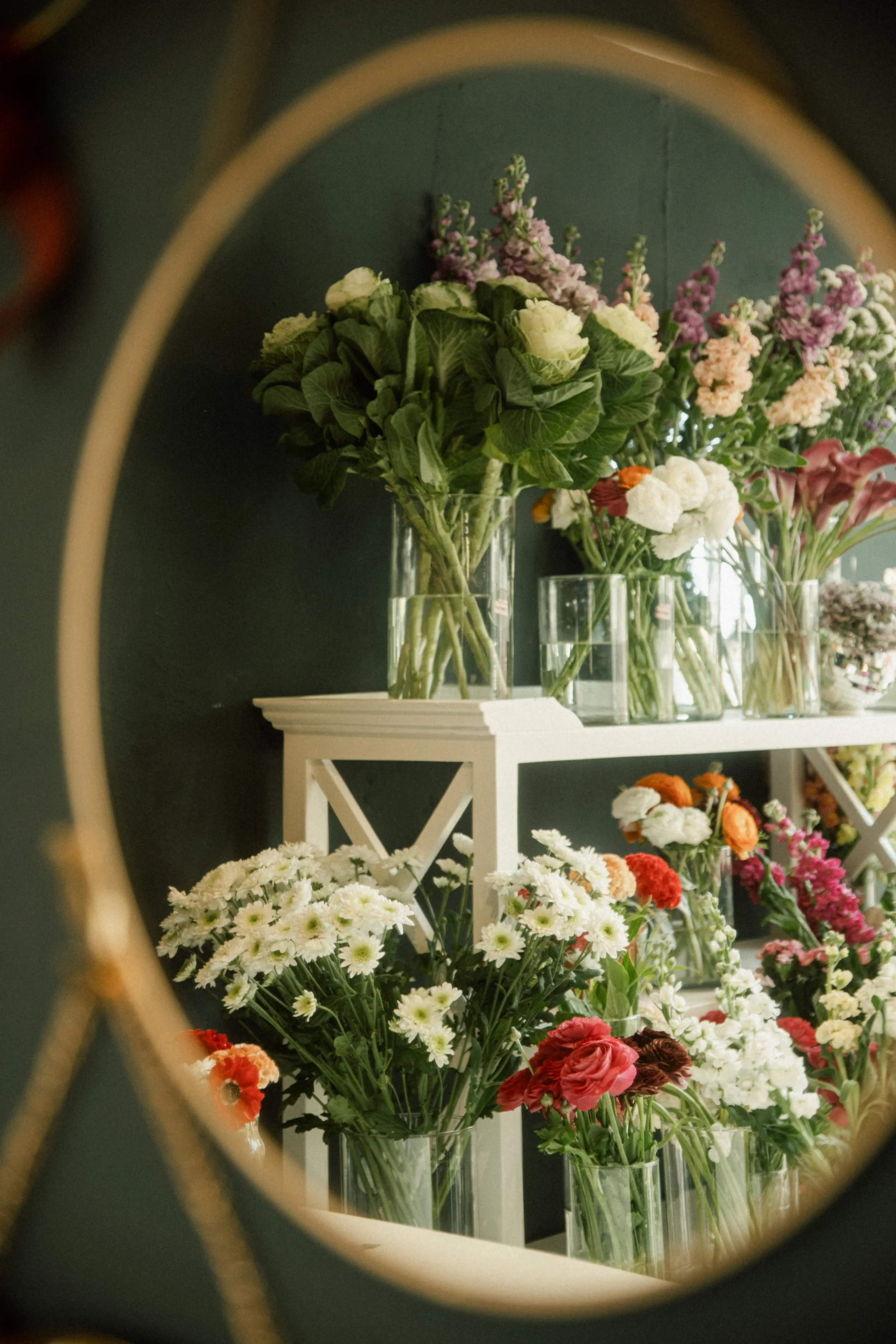 Vases avec des fleurs colorées dans une boutique, vues à travers un miroir rond