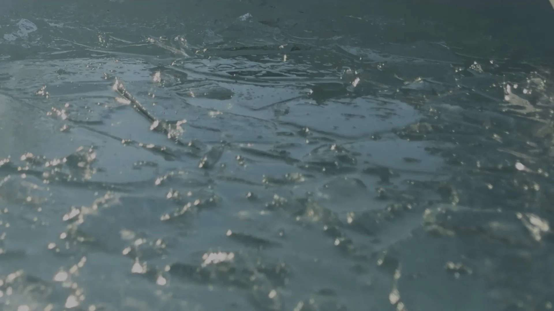 Close-up of a body of water with floating debris and small splashes.