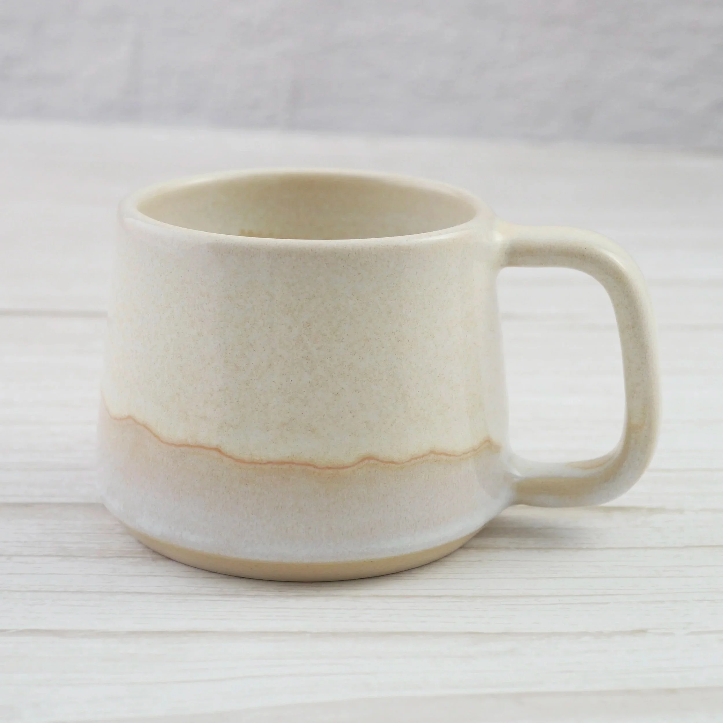 Hand-thrown stoneware mug. This mug features a beautiful blend of beige and white glazes, creating organic, flowing patterns that make every piece uniquely yours.