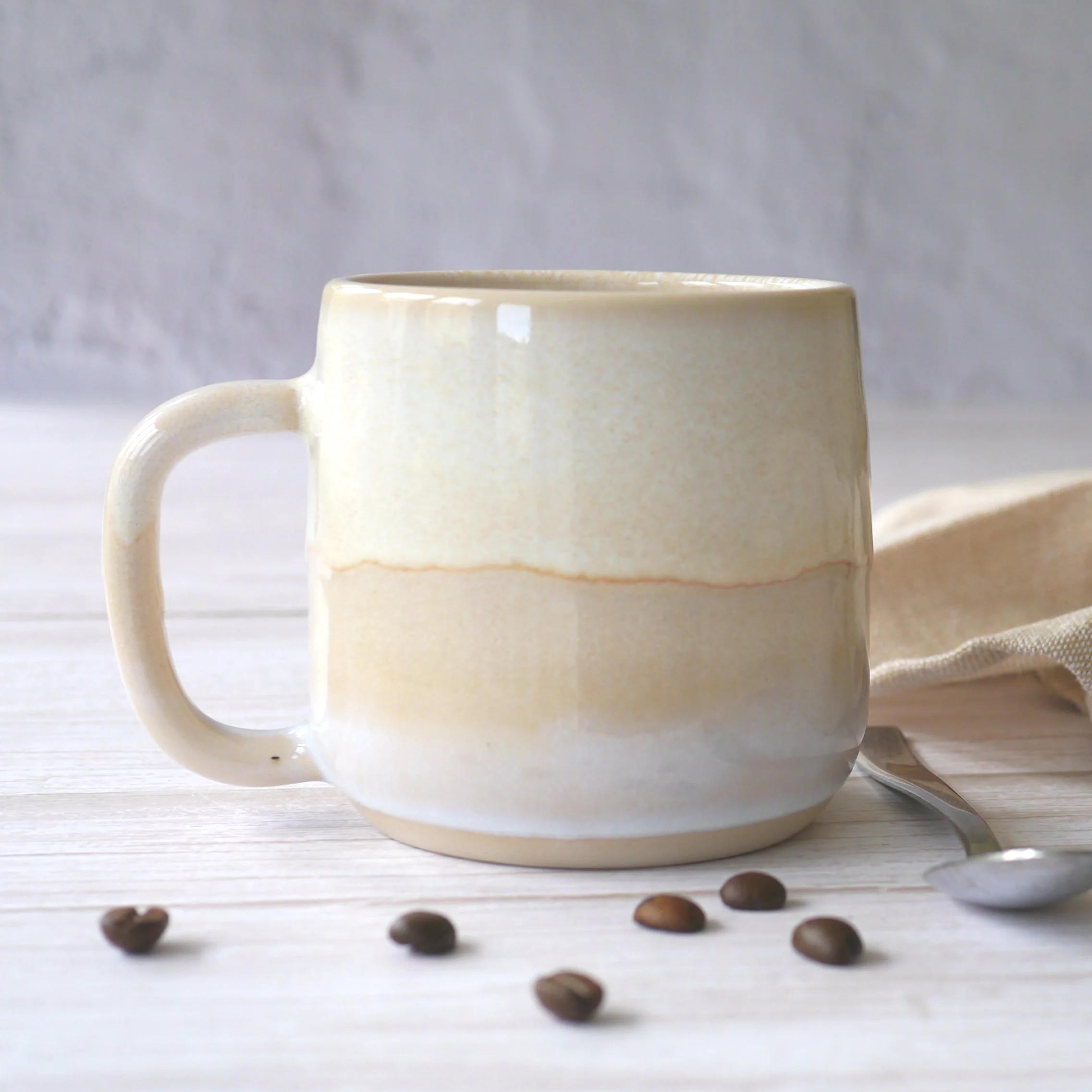 Hand-thrown stoneware mug. This mug features a beautiful blend of beige and white glazes, creating organic, flowing patterns that make every piece uniquely yours.