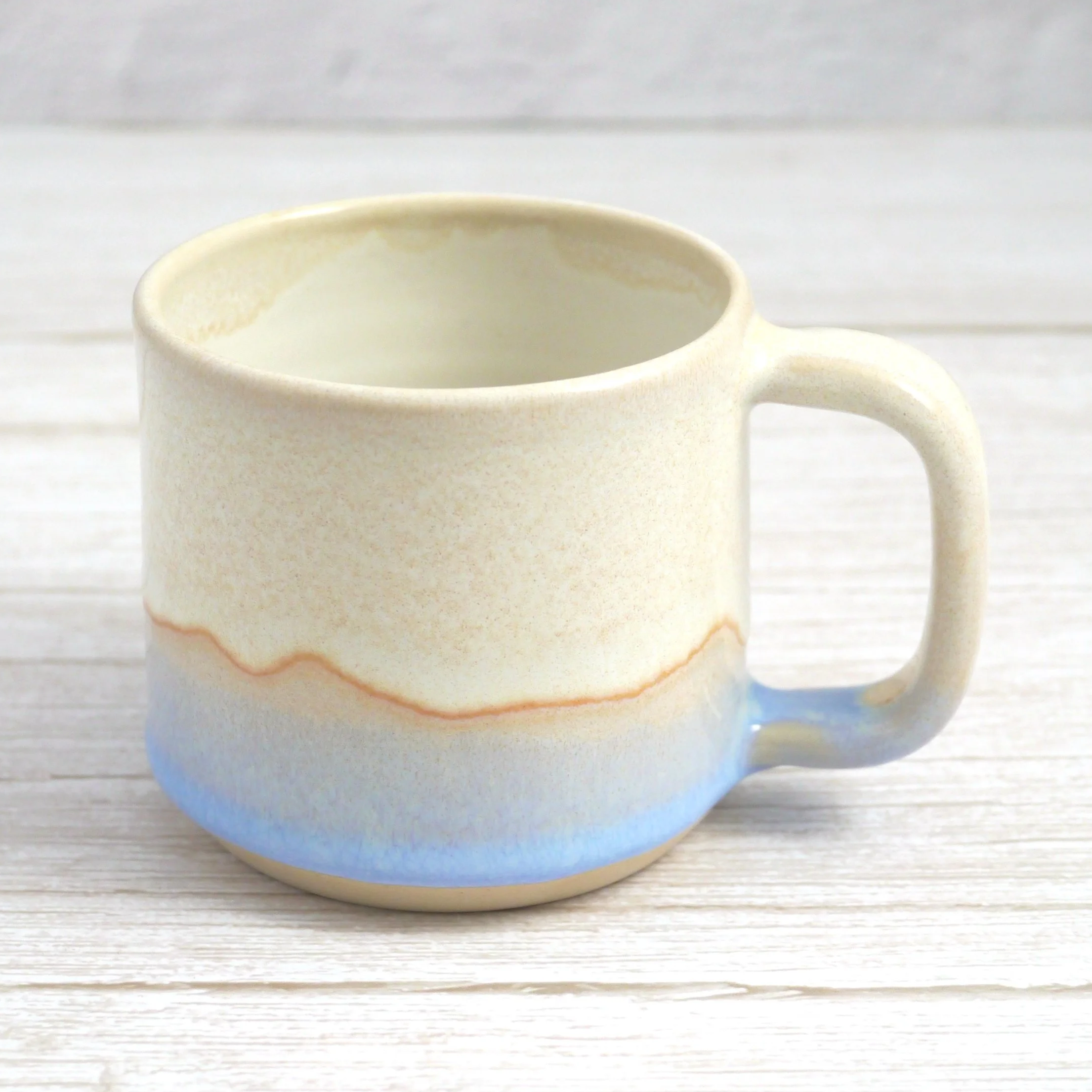 Hand-thrown stoneware mug. This mug features a beautiful blend of beige and blue glazes, creating organic, flowing patterns that make every piece uniquely yours.