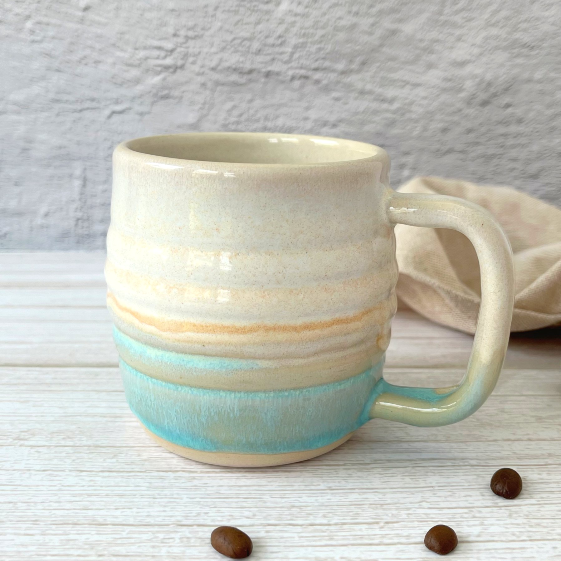 handmade ceramic mug in a cream and turquoise glaze with a soft rippled exterior