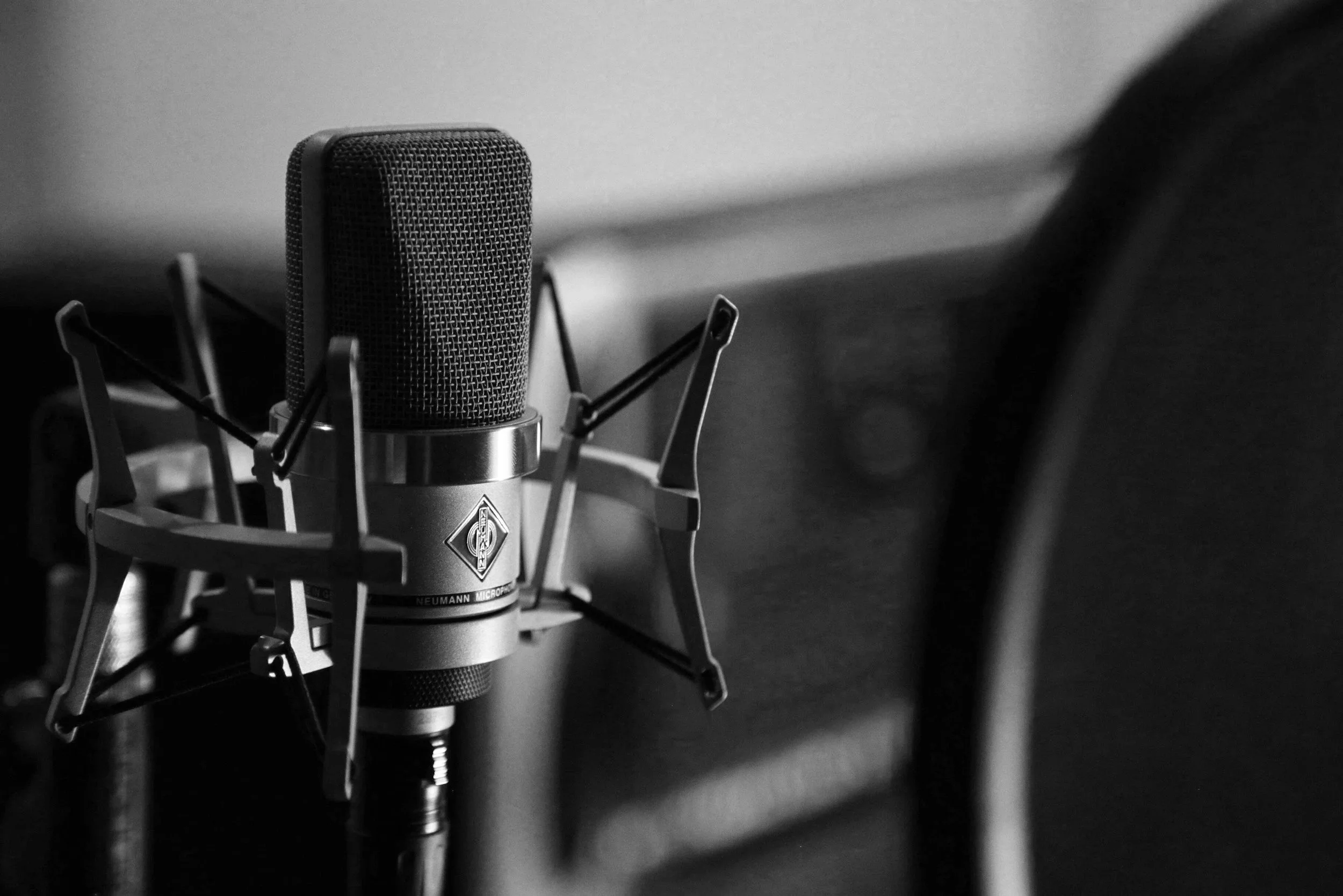 Close-up of a professional microphone on a stand in a recording studio, in black and white.