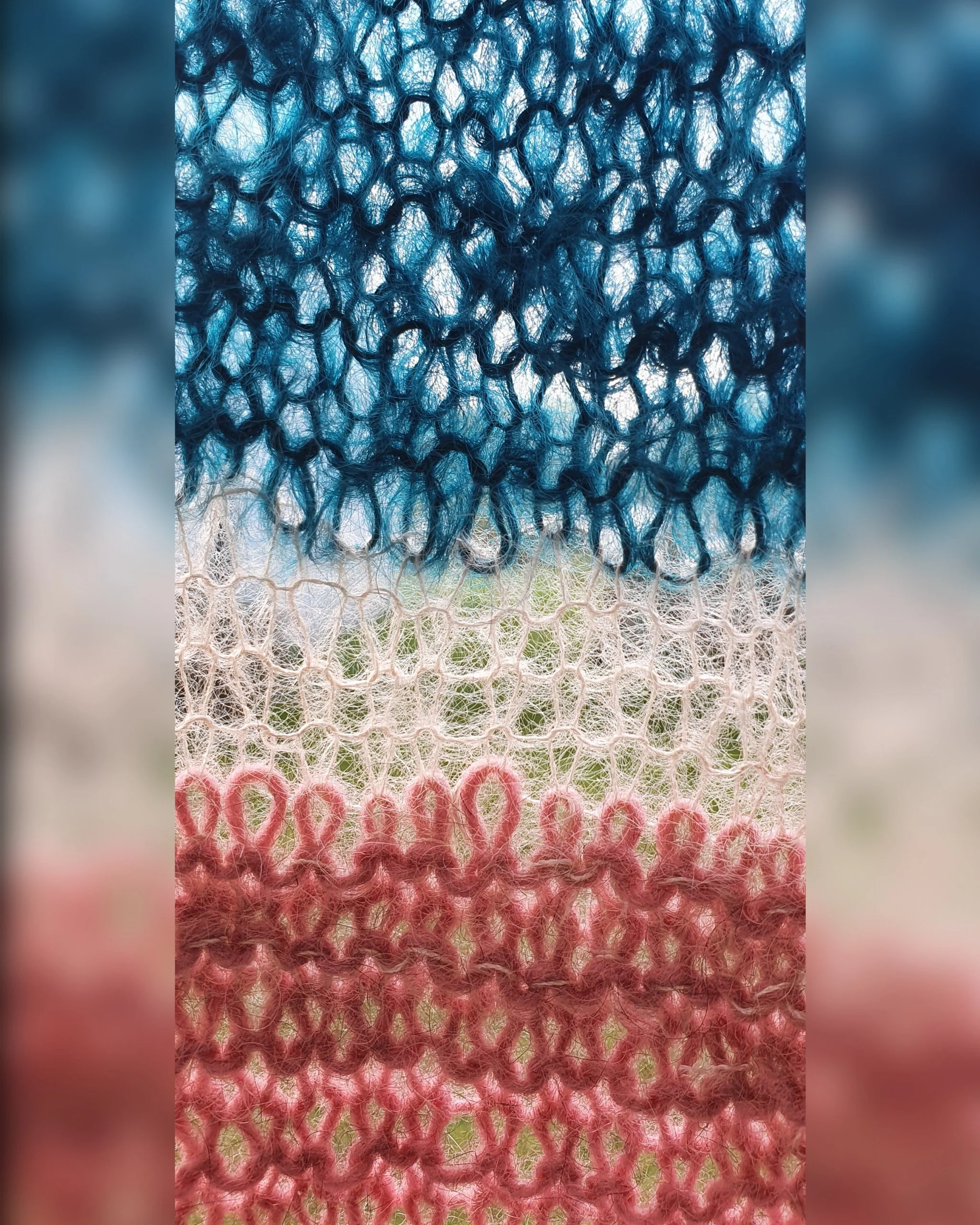 Close-up of a knitted fabric with horizontal stripes in blue, white, and pink.