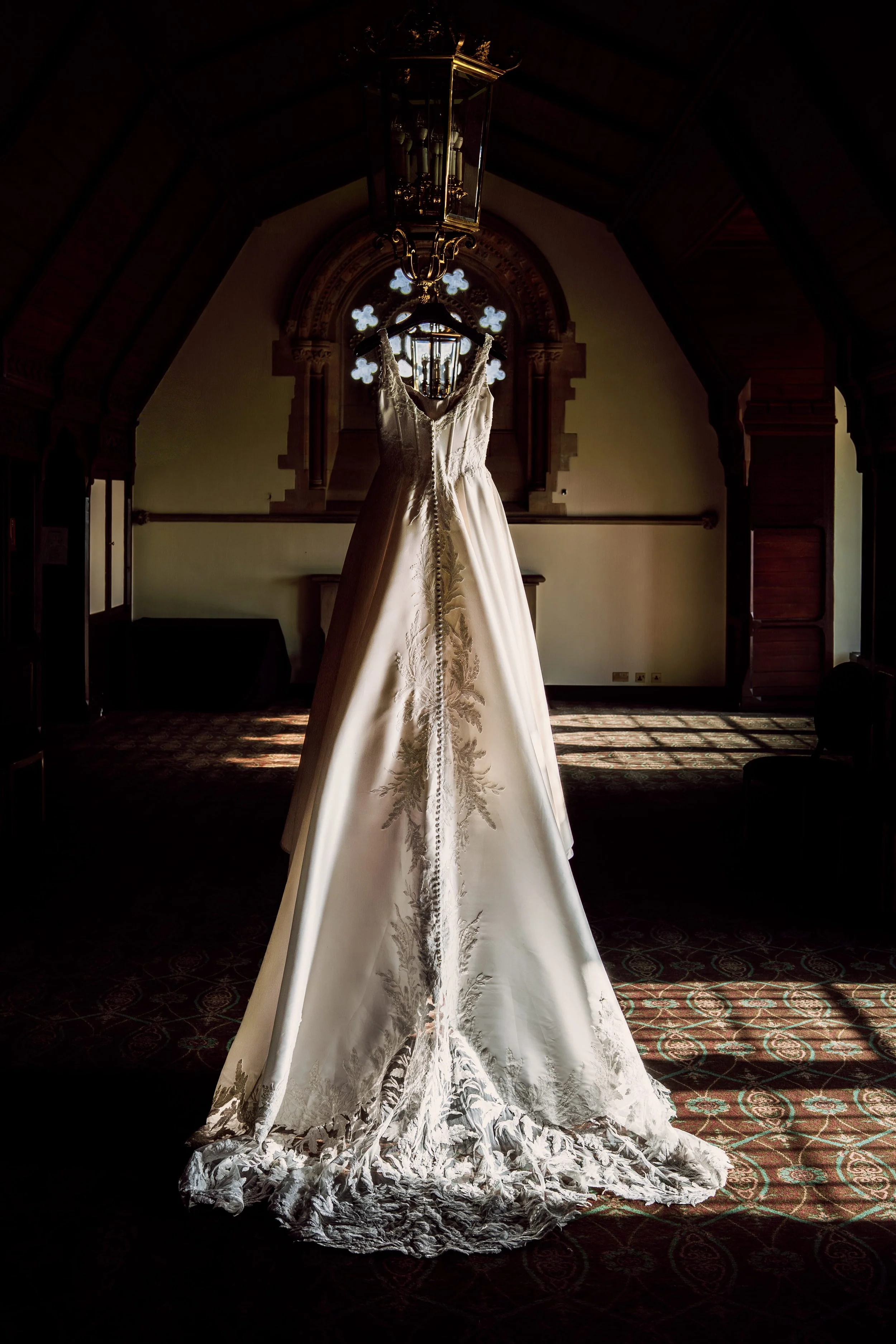 Wedding dress hanging in the long gallery at Ettington park Hotel