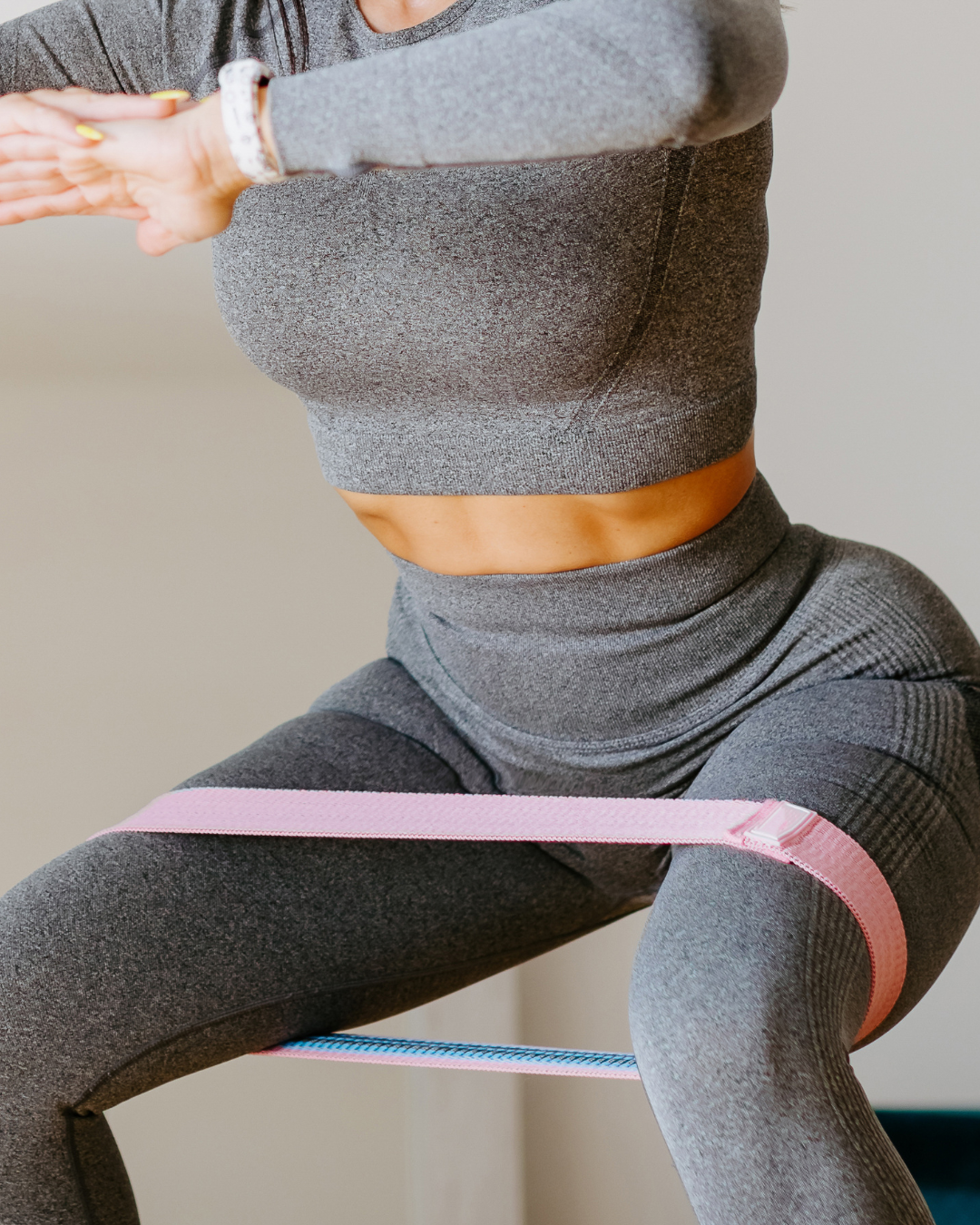 Persona haciendo ejercicio con bandas de resistencia en las piernas y en la parte superior del cuerpo, ropa deportiva gris