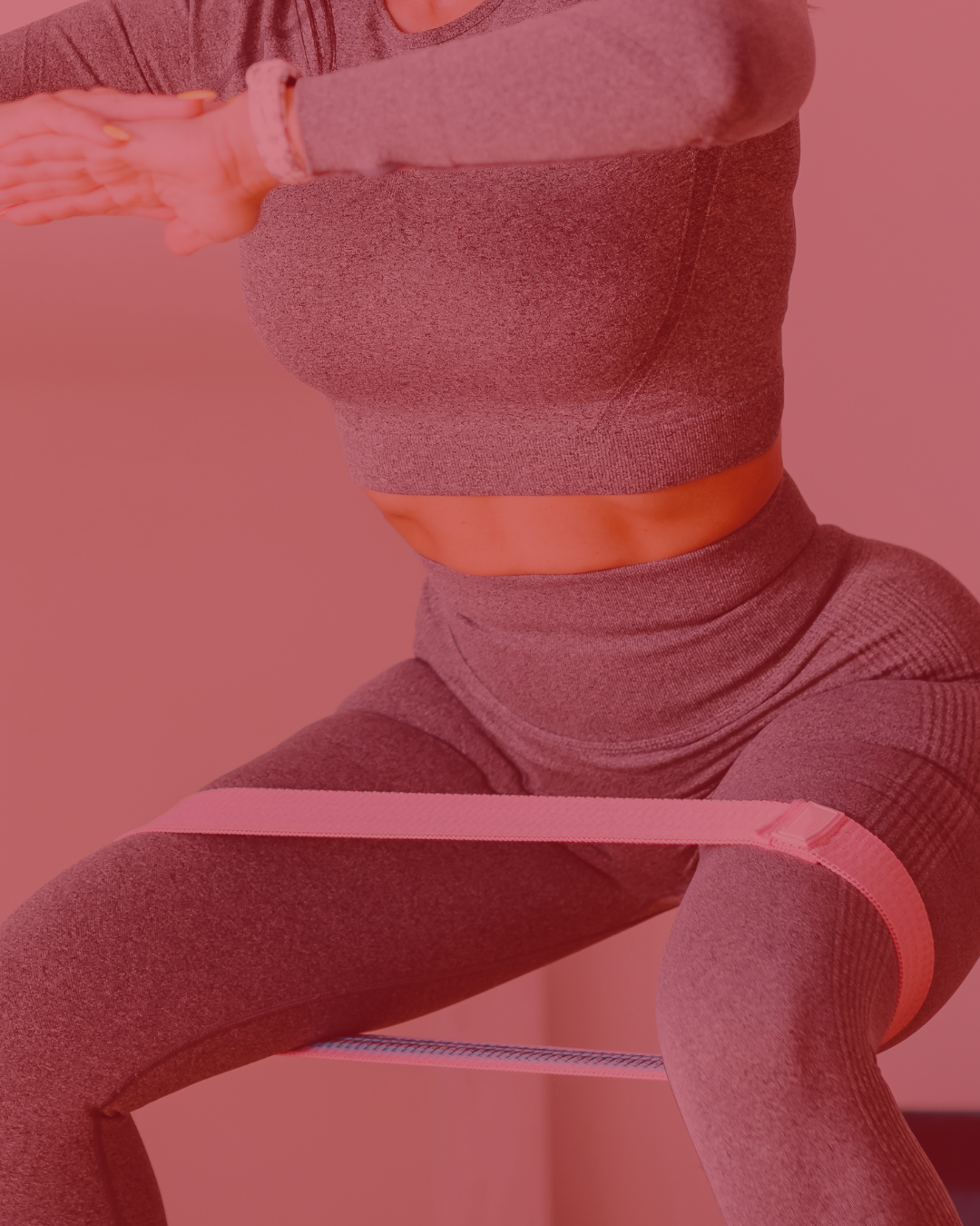 Persona haciendo ejercicio con banda de resistencia, vistiendo ropa deportiva gris, en un fondo rosa.