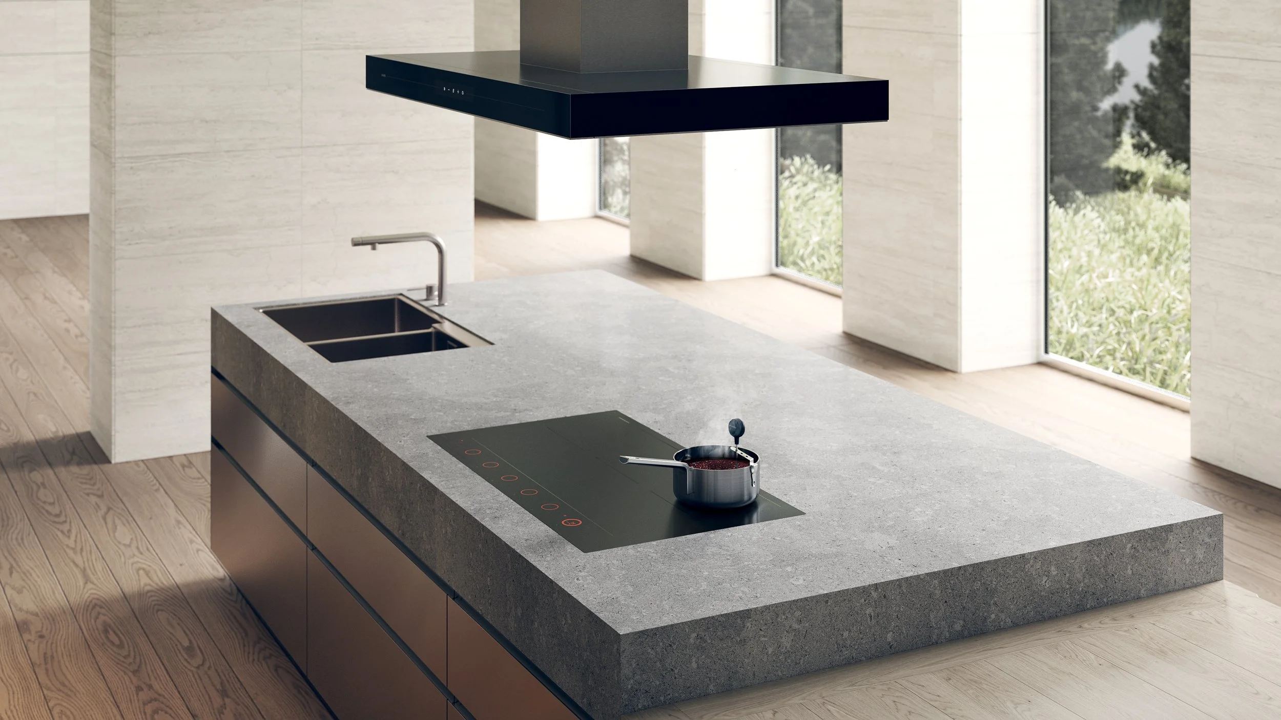 Modern kitchen with a gray stone countertop, induction stovetop with a pot on it, stainless steel sink, black range hood, and large windows with a view of greenery outside.
